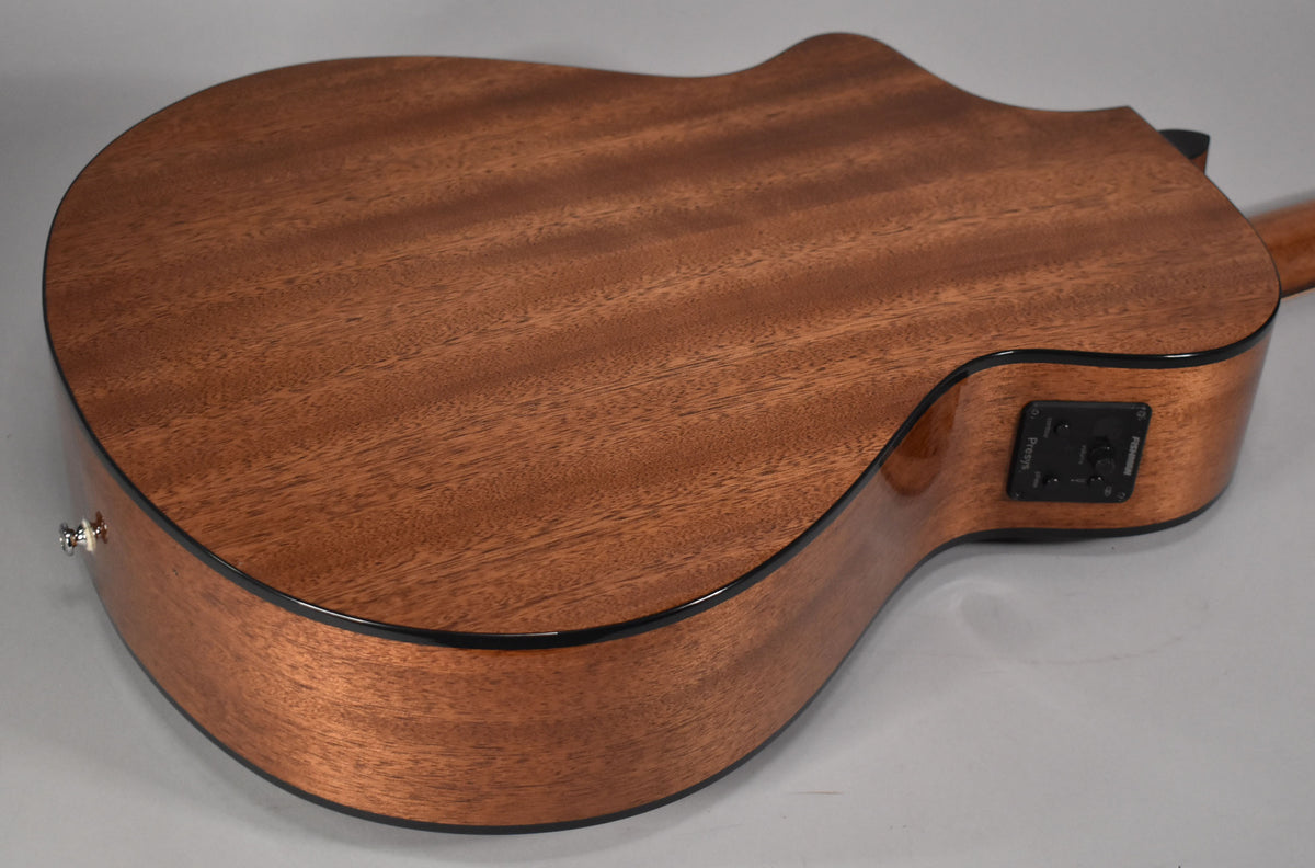 The guitar's mahogany back and sides are visible from the lower bout, with a black preamp control panel on the upper side.