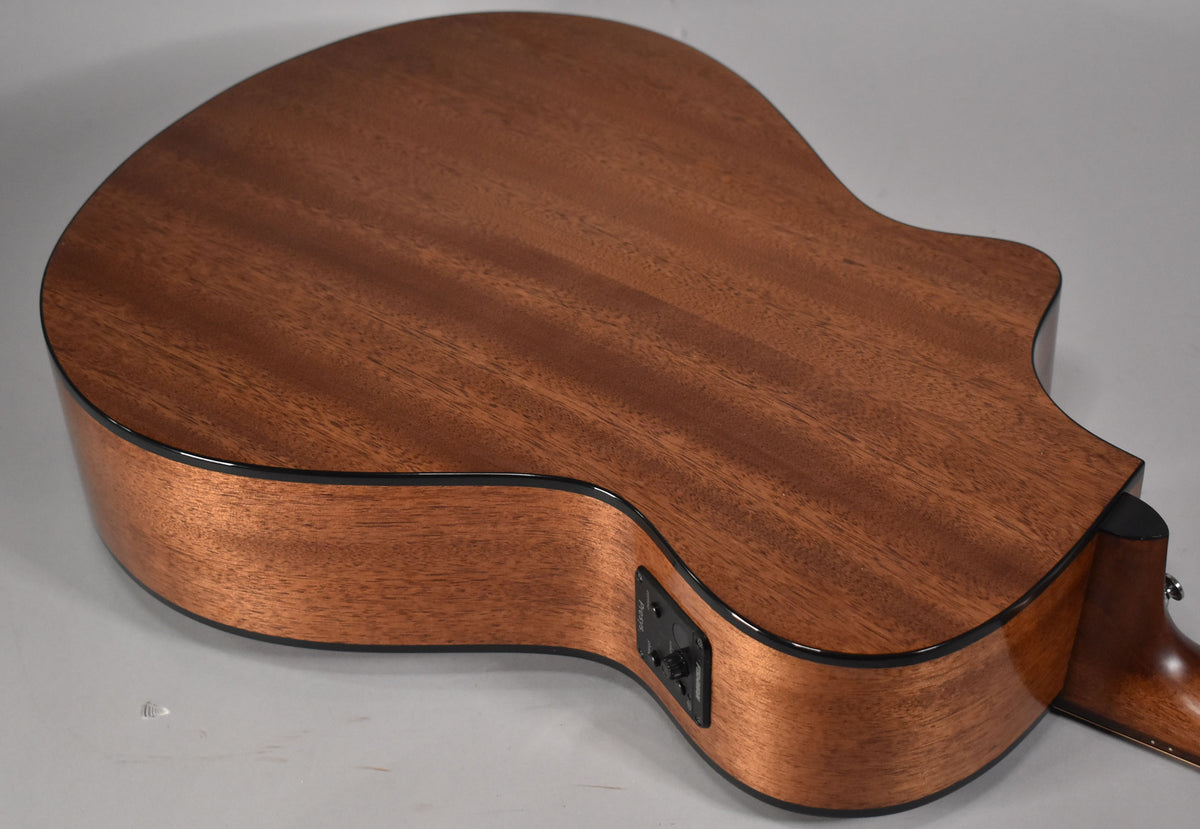 The acoustic guitar's mahogany back and sides are visible from the lower bout, with a black preamp control panel on the cutaway.