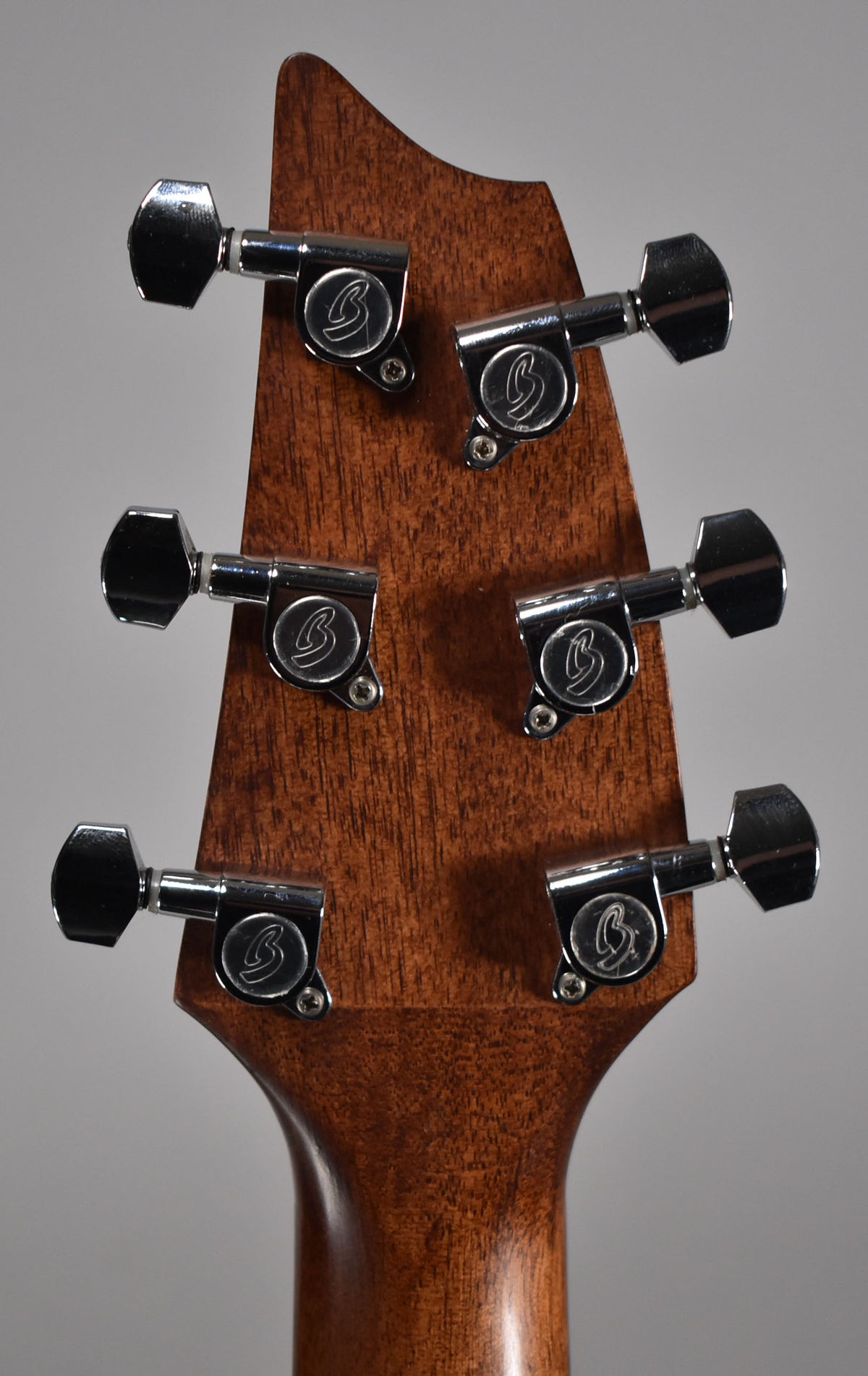 Rear view of the mahogany headstock and neck, showing six chrome tuners with a "B" logo, in excellent condition.