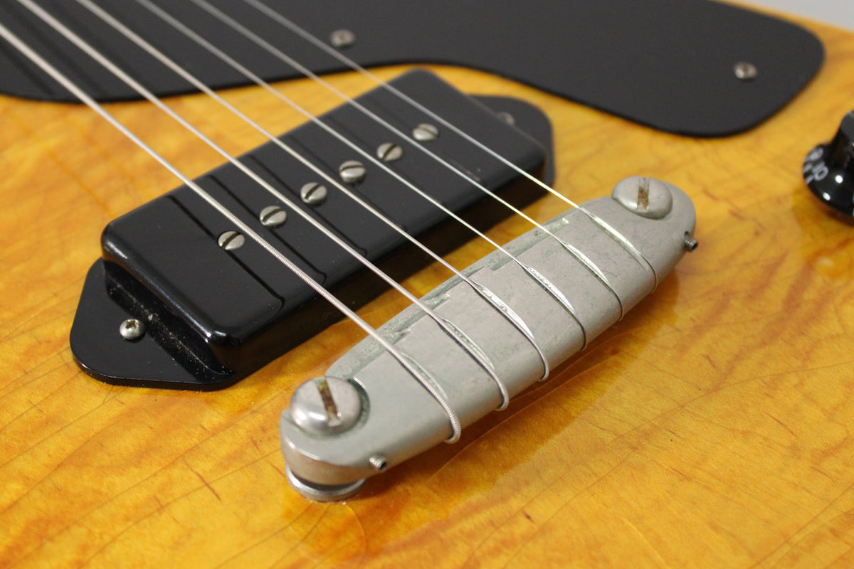 Close-up of the amber nitro body, showing a black P90 pickup, aged wraparound bridge, and a black volume knob.