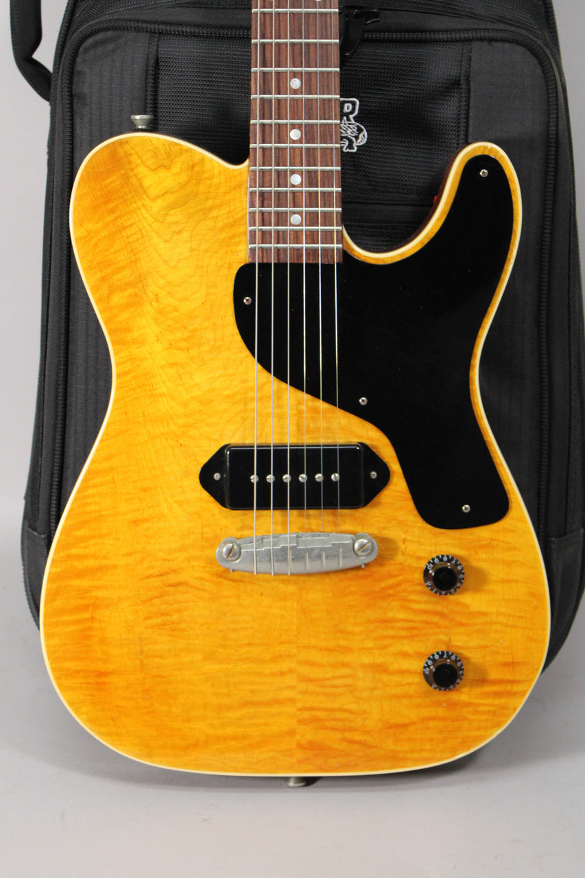 The amber nitro guitar body, with a black pickguard and P90 pickup, shows light aging and two black control knobs.