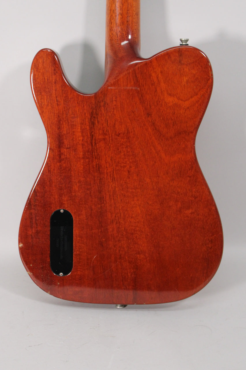 The guitar's amber nitro finish shows wood grain, a black control plate, and light wear on the lower bout and strap button.
