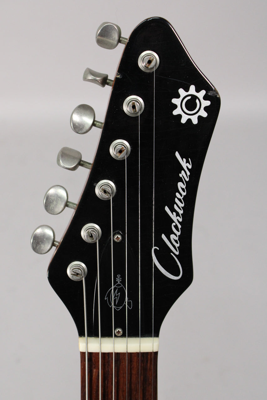 Close-up of the black headstock with six aged nickel tuners, showing light wear and a small chip on the top edge.