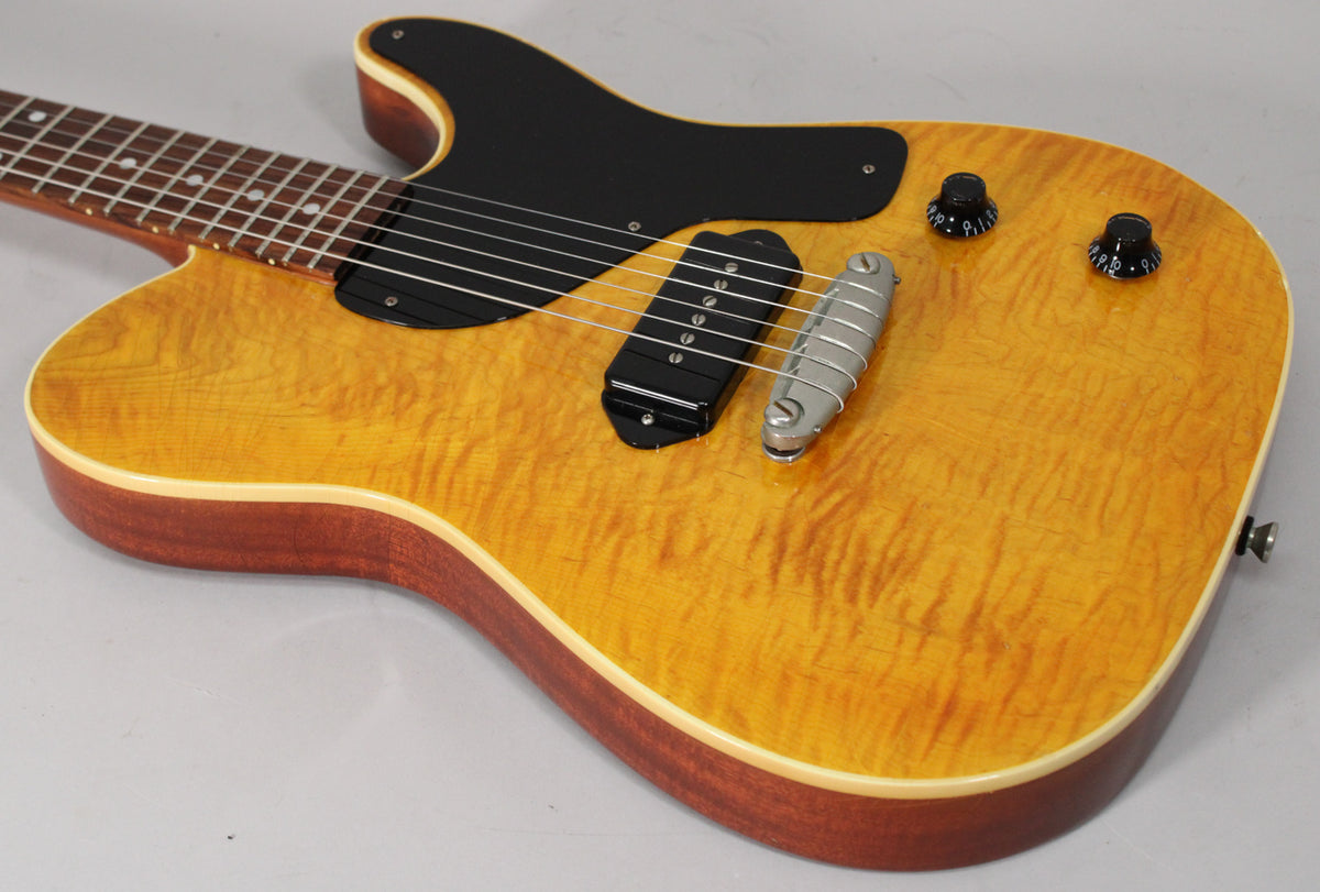 Close-up of the guitar body, showing the amber flamed maple top, black pickguard, P90 pickup, and two black control knobs.