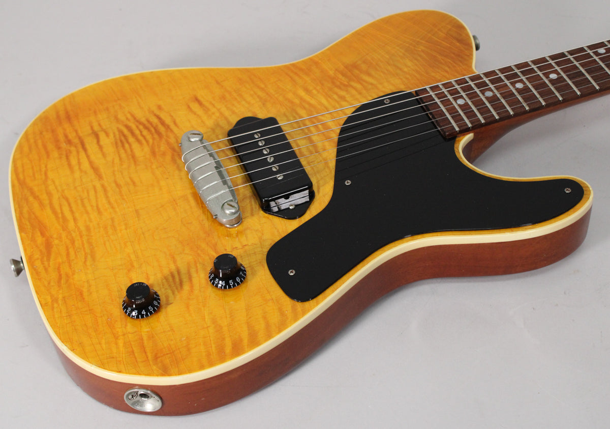 Close-up of the aged amber nitro guitar body, showing a single P90 pickup, black pickguard, and two black control knobs.