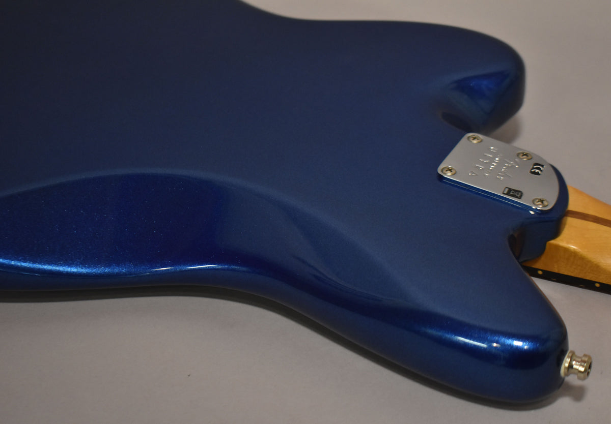 The guitar's cobalt blue metallic body, with a satin finish, is shown from the back, revealing the neck plate and output jack.