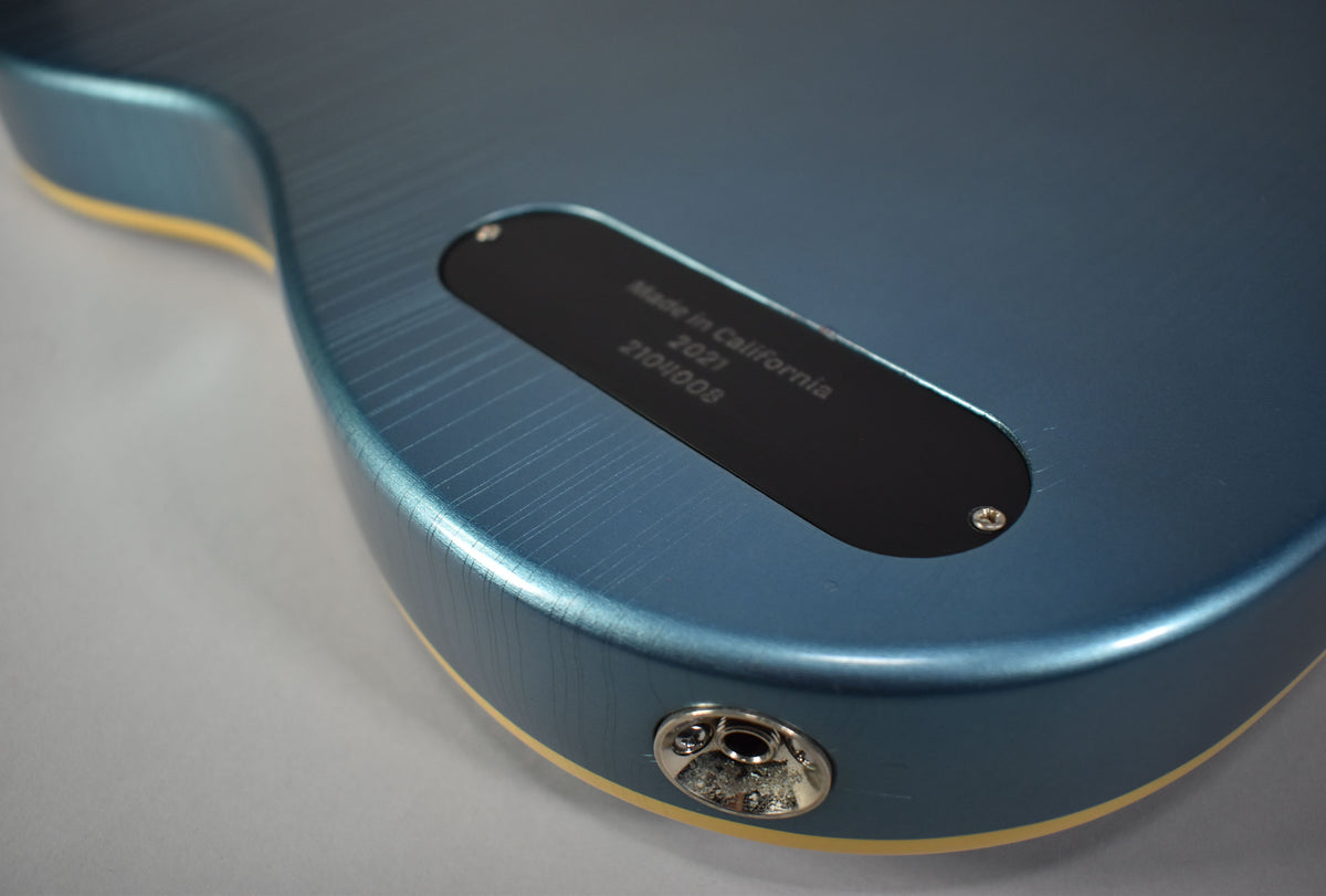 Close-up of the metallic Pelham Blue guitar body with heavy finish checking, a black control plate, and a chrome output jack.