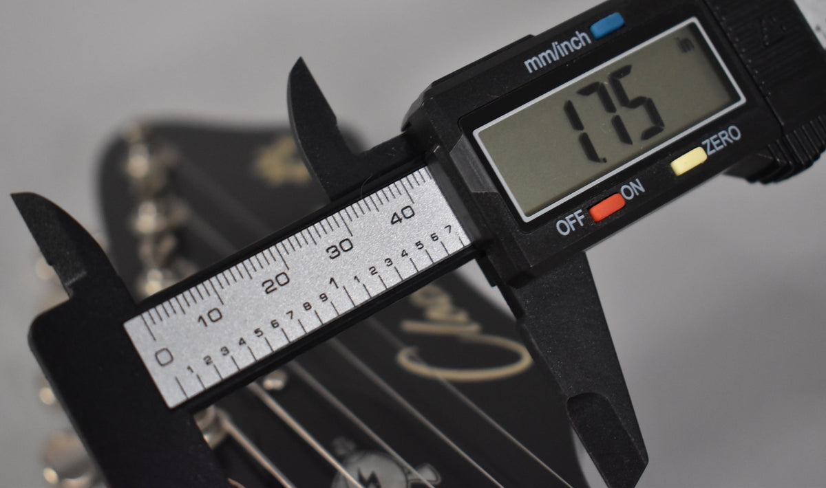 A digital caliper measures the guitar's nut, displaying "1.75" inches.