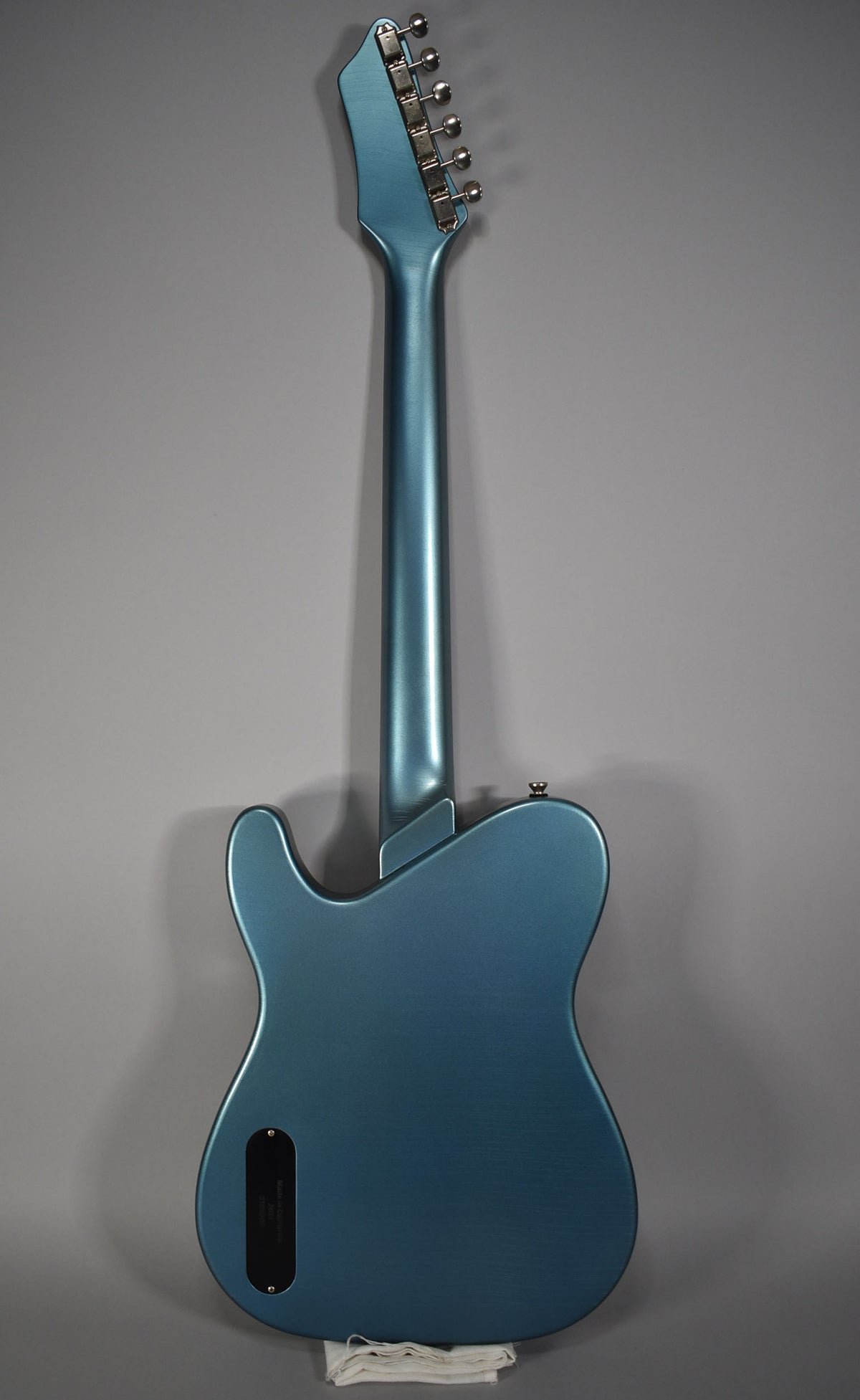 Full back view of a metallic Pelham blue guitar with a matte finish, showing the neck, headstock with six tuners, and control cavity cover.