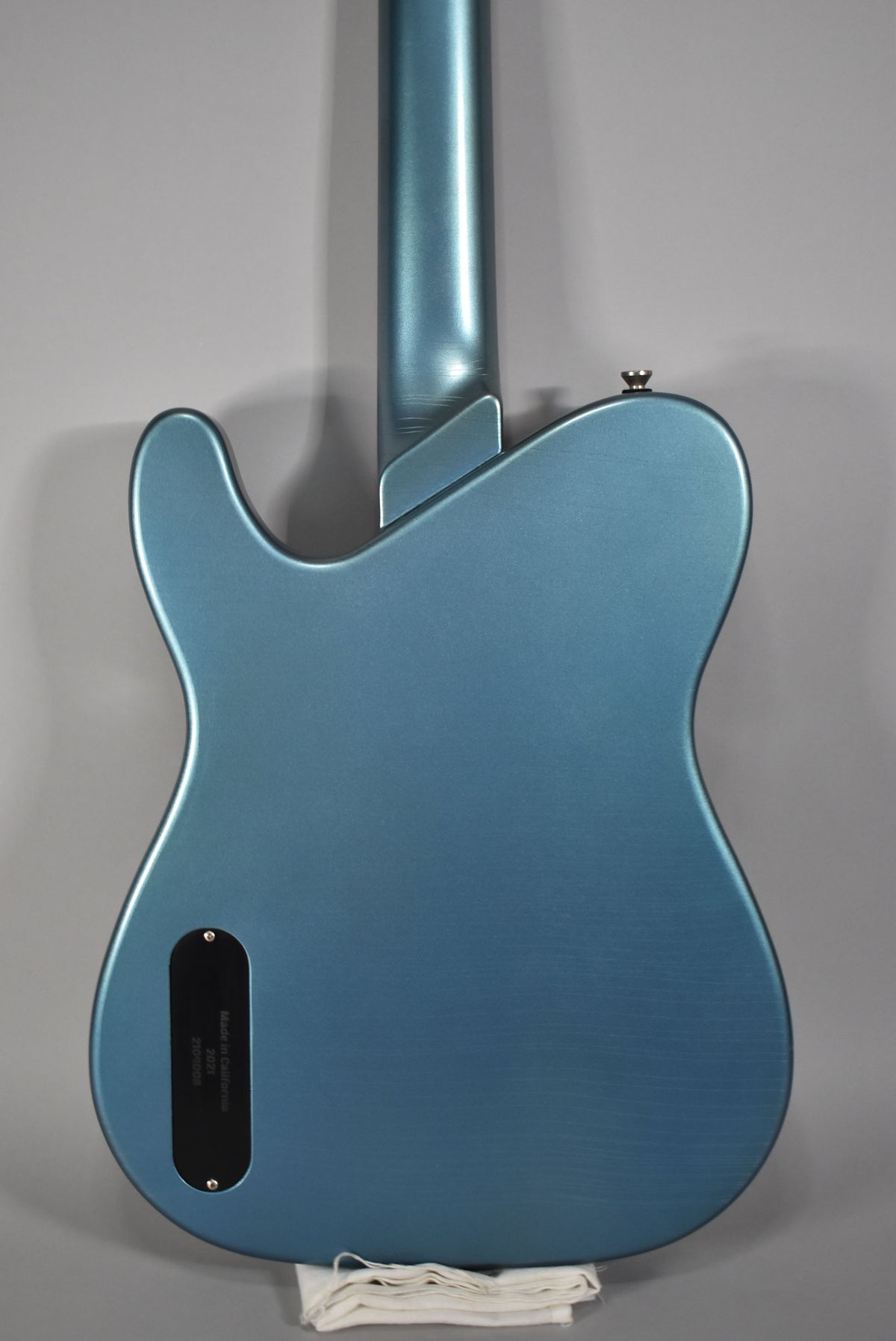 The back of a metallic Pelham blue guitar with a satin finish, showing light wear on the neck and body.