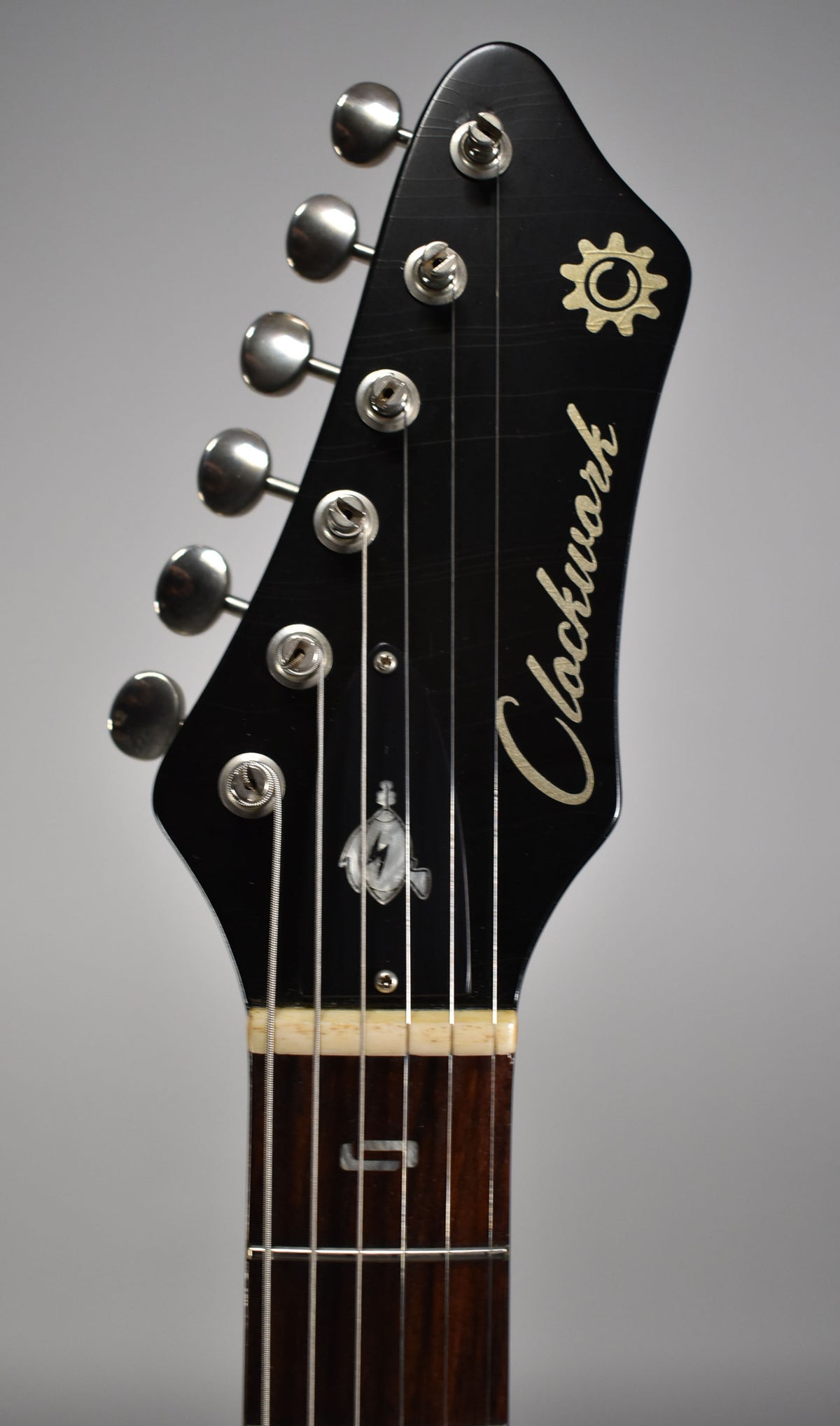 Close-up of the black headstock with six chrome tuners, showing the nut and the first fret of the dark fretboard.