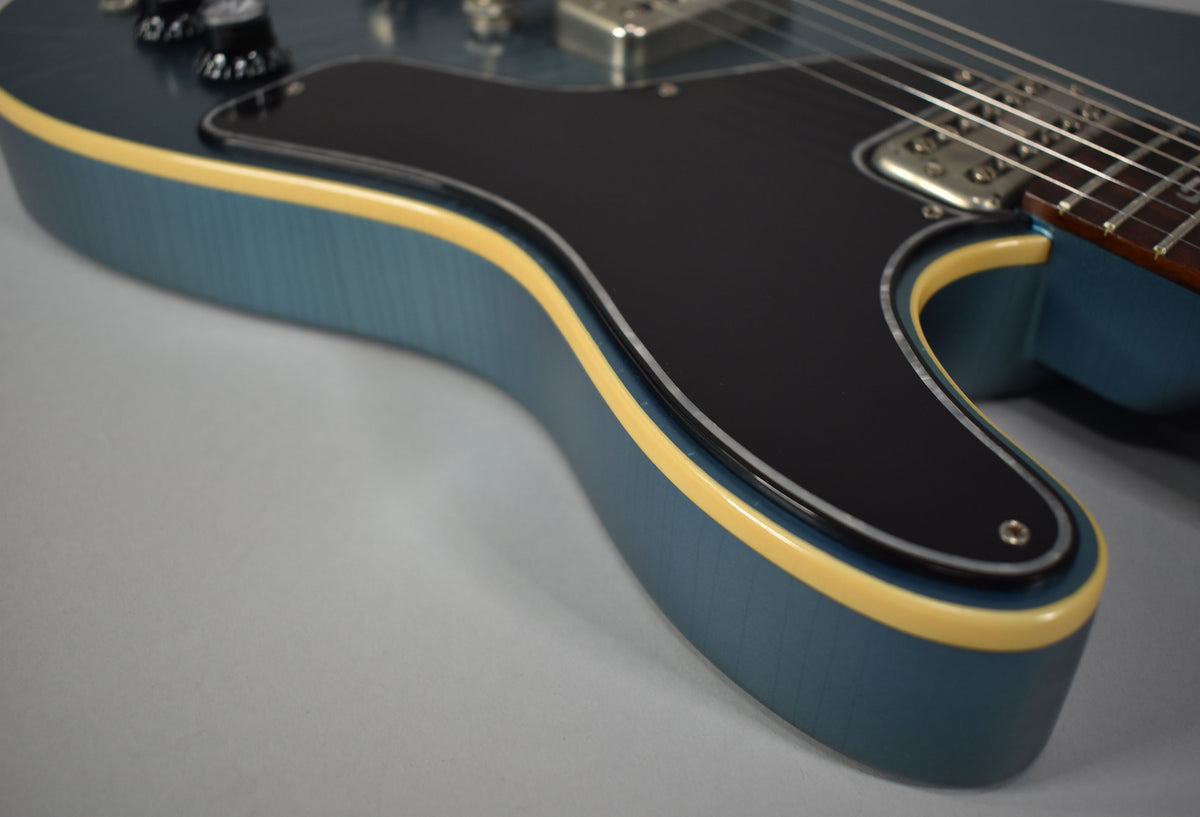 Close-up of the guitar's lower bout, showing the metallic Pelham blue finish, cream binding, and black pickguard with a single screw.