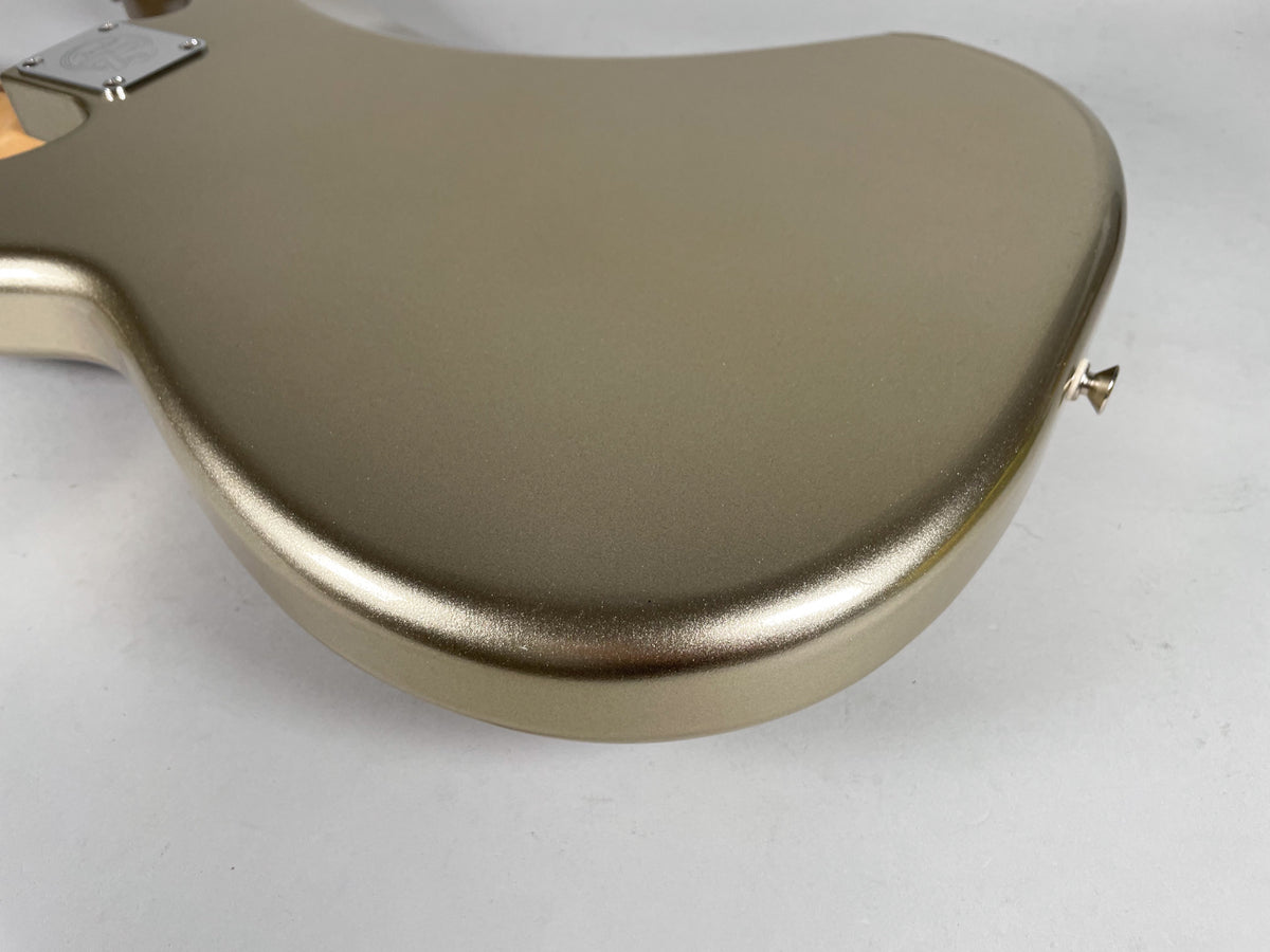 Close-up of the bass's lower body, showing the metallic gold finish and the strap button on the bottom edge.