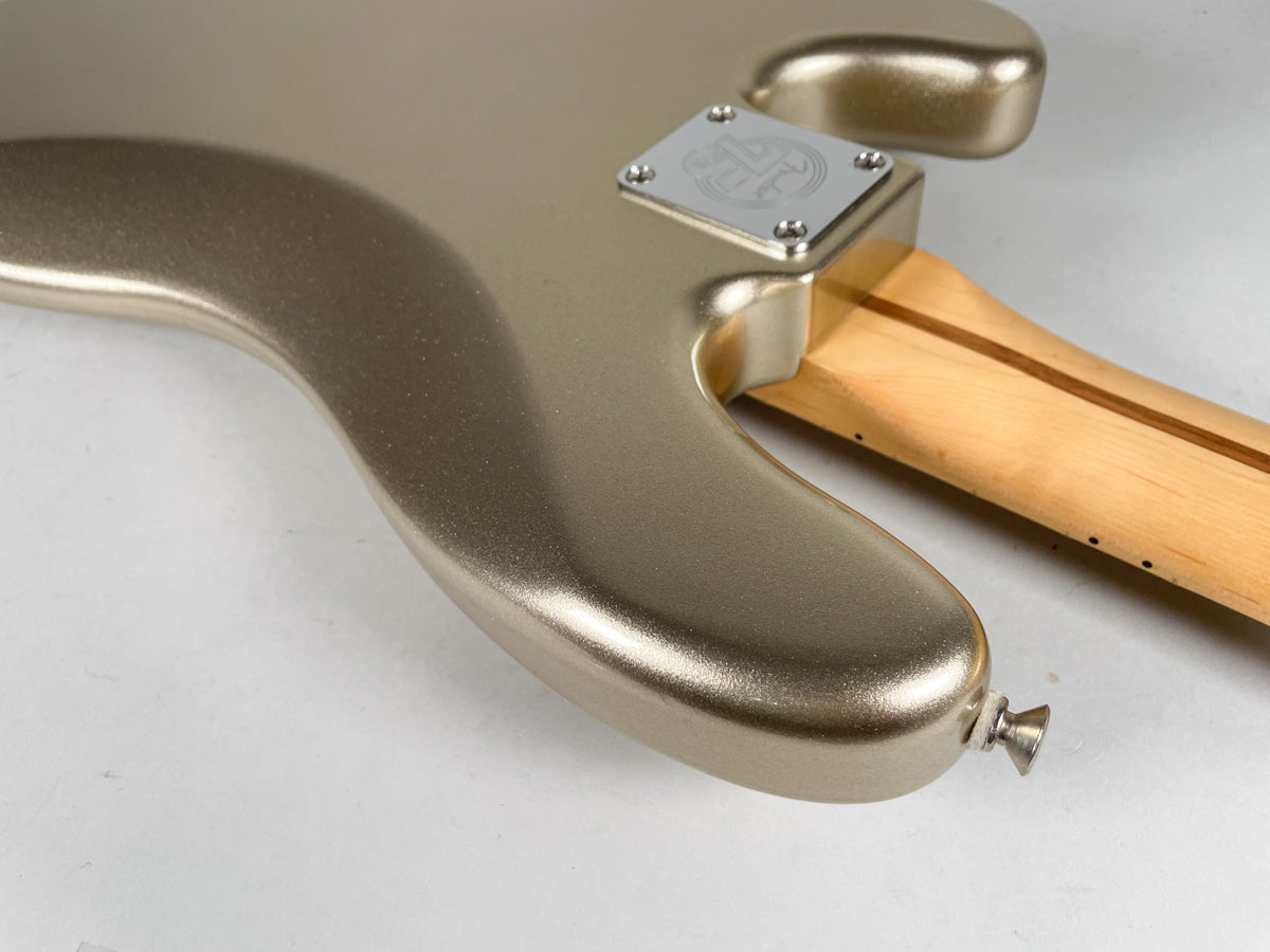 The bass body's lower horn and neck joint are visible, showing the metallic gold finish, chrome neck plate, and strap button.