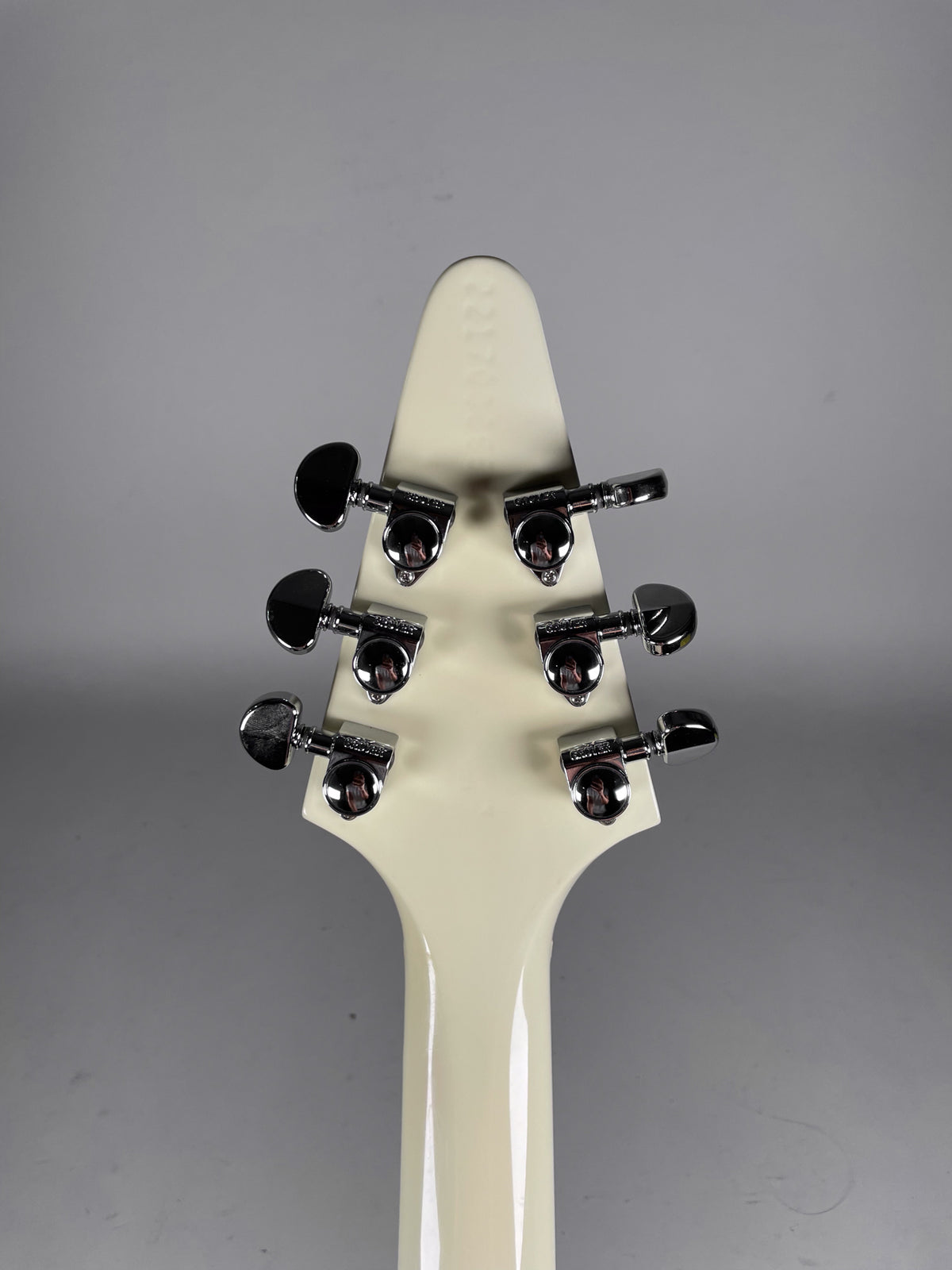 The back of the white headstock and top of the neck, showing six chrome tuners with black kidney-bean buttons.
