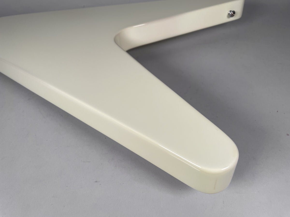 Close-up of the guitar's lower wing in glossy white, showing a slight scuff on the rounded tip and a strap button on the upper wing.