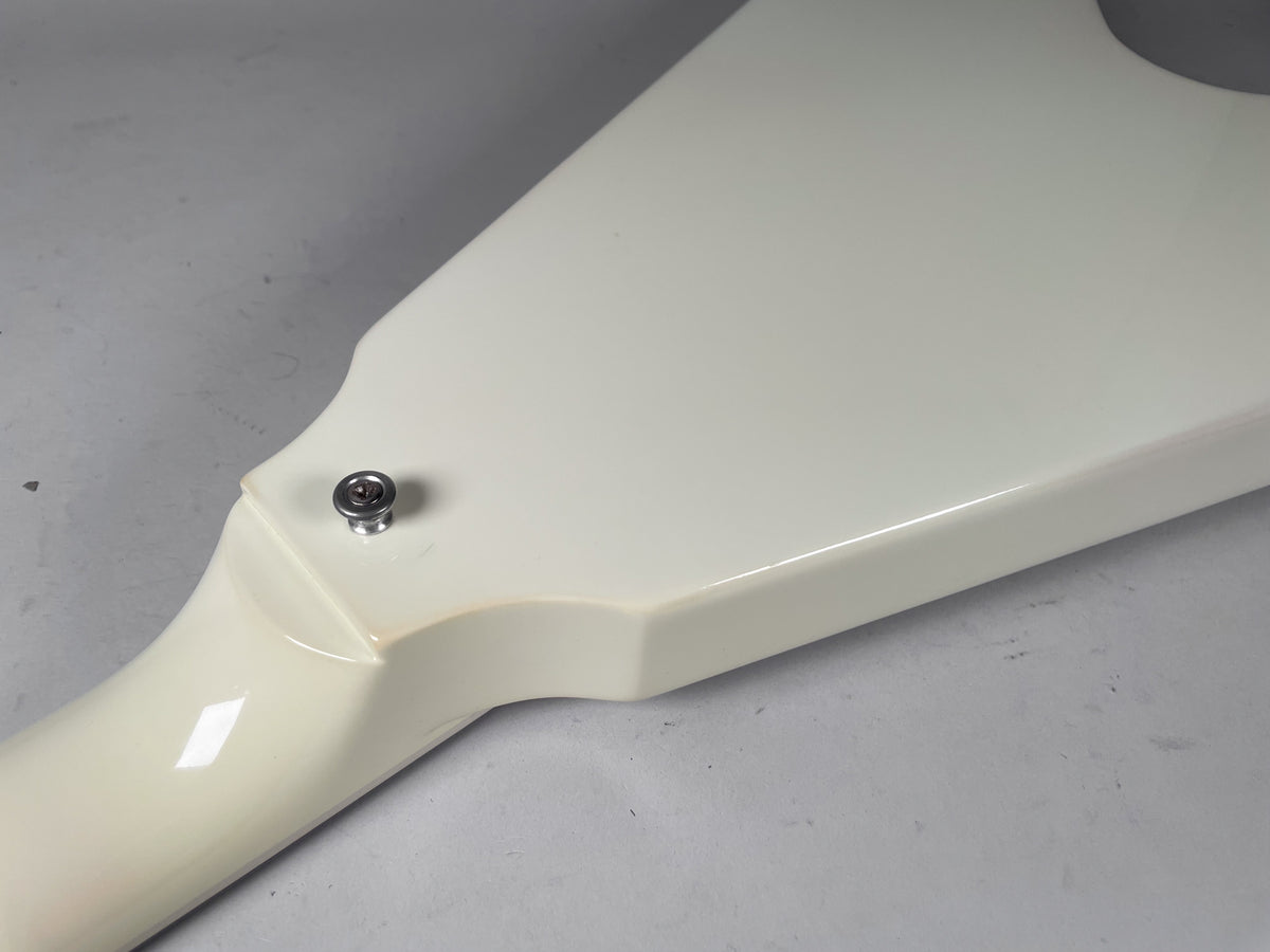 Close-up of the guitar's neck heel and lower body in white, showing the strap button and a slight yellowing of the finish.