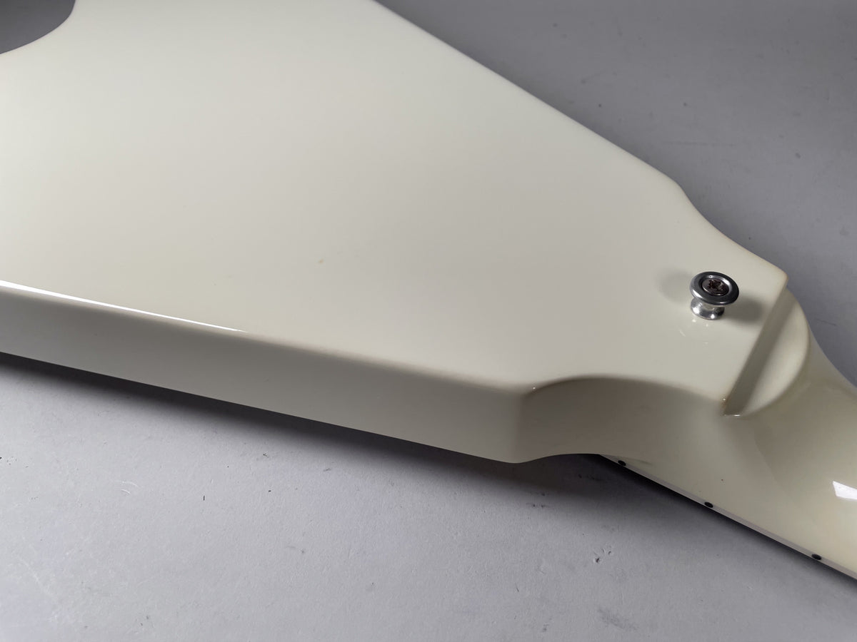 Close-up of the guitar's lower body, showing the glossy white finish and a chrome strap button near the neck joint.