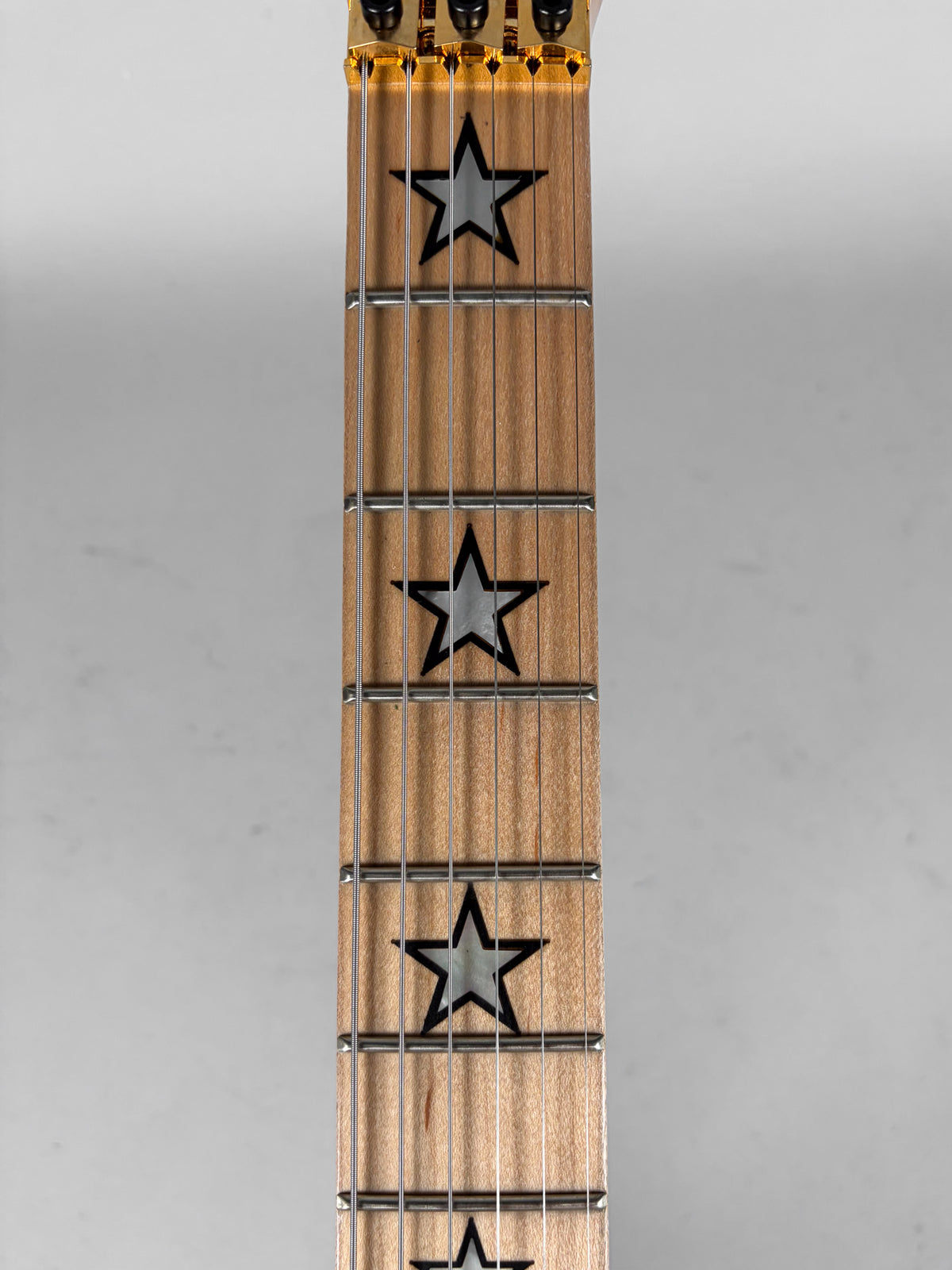 Close-up of a guitar fretboard with light wood, metal frets, and star-shaped inlays.