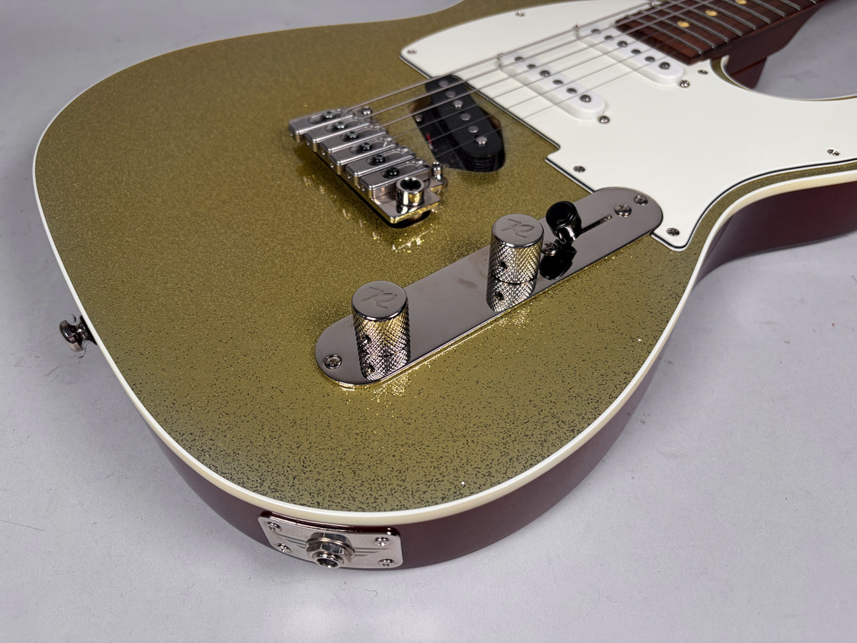 The guitar's lower body is angled, showing its gold sparkle finish, white pickguard, chrome bridge, control plate, and input jack.