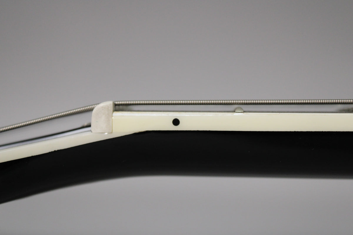 Close-up of the guitar's cream-bound neck, showing the side dots, a single string, and the nut against a dark background.