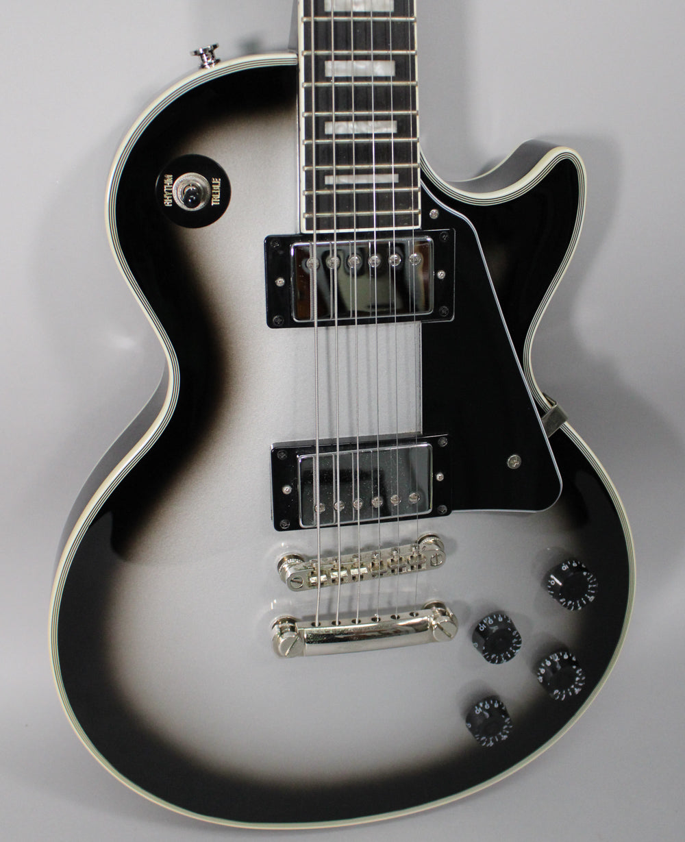 The guitar's body is framed from the neck joint down, showing a silverburst finish with chrome hardware and black control knobs.