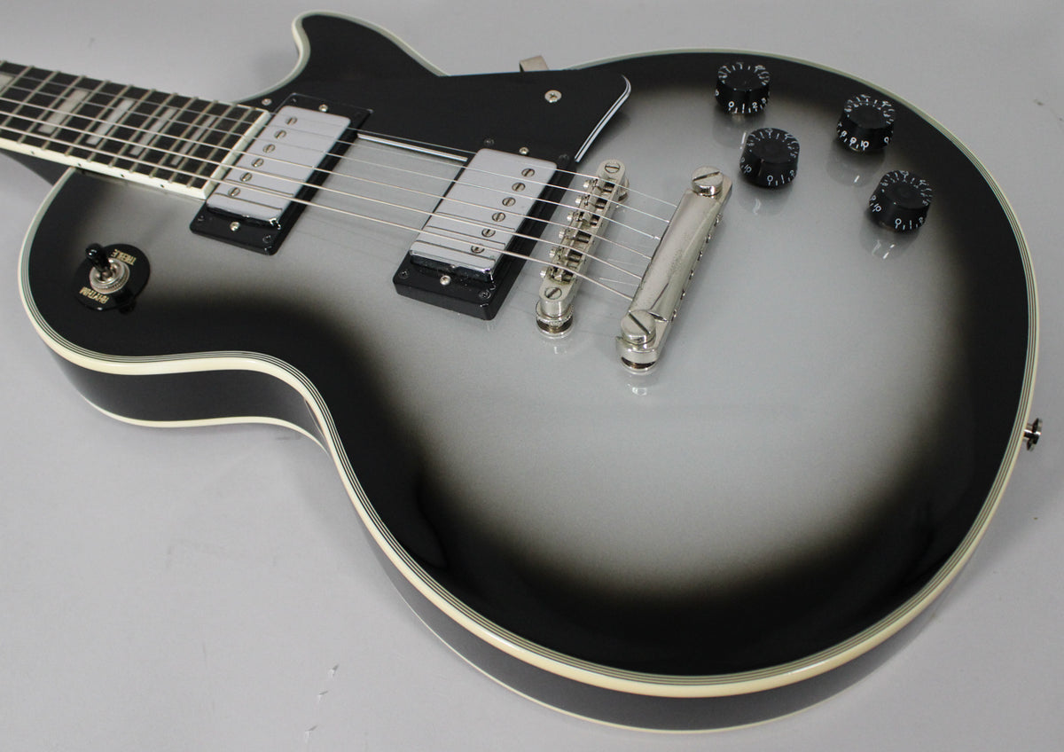 The Silverburst Les Paul's body is angled from the neck, showing its chrome hardware, black pickguard, and four black control knobs.