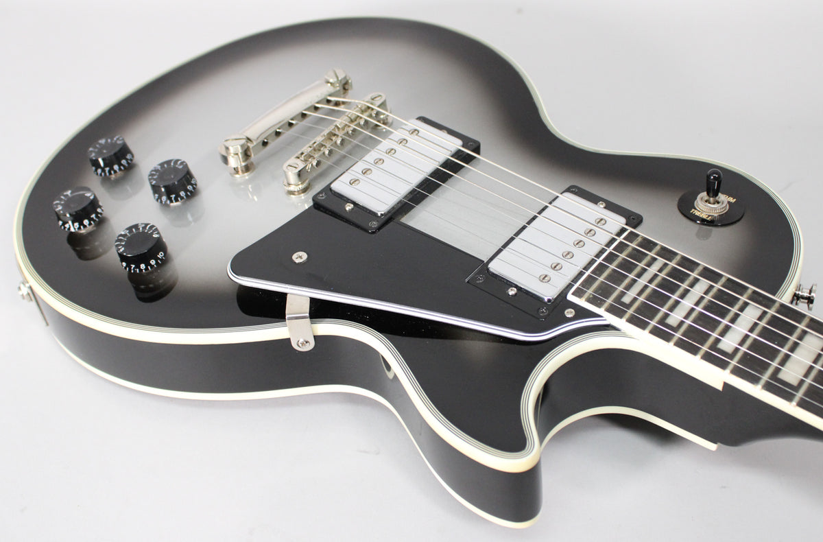 Close-up of the guitar's body, showing the silverburst finish, black pickguard, four black control knobs, and two humbucker pickups.