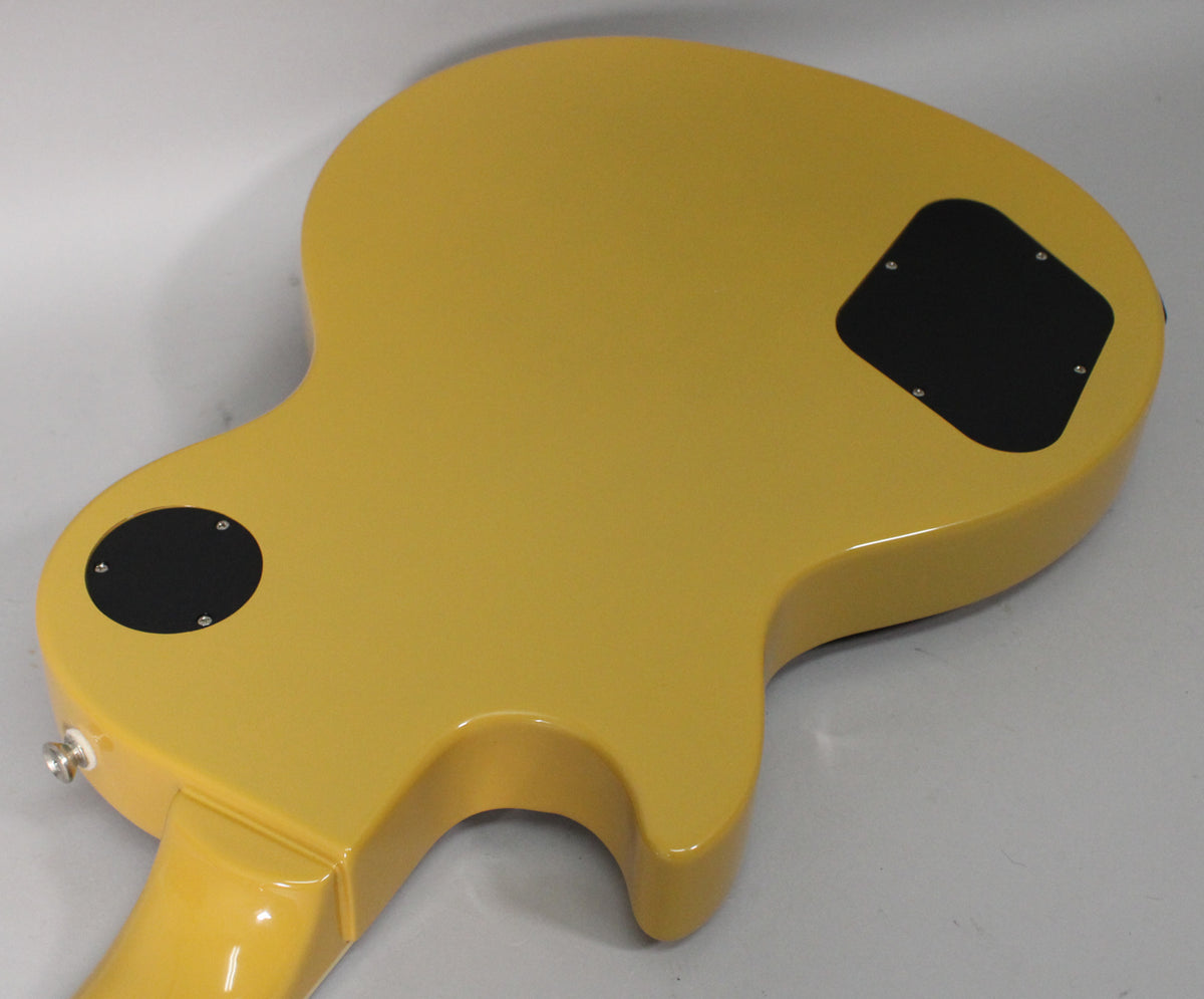 The back of a glossy TV yellow guitar body, showing two black control cavity covers and a chrome output jack.
