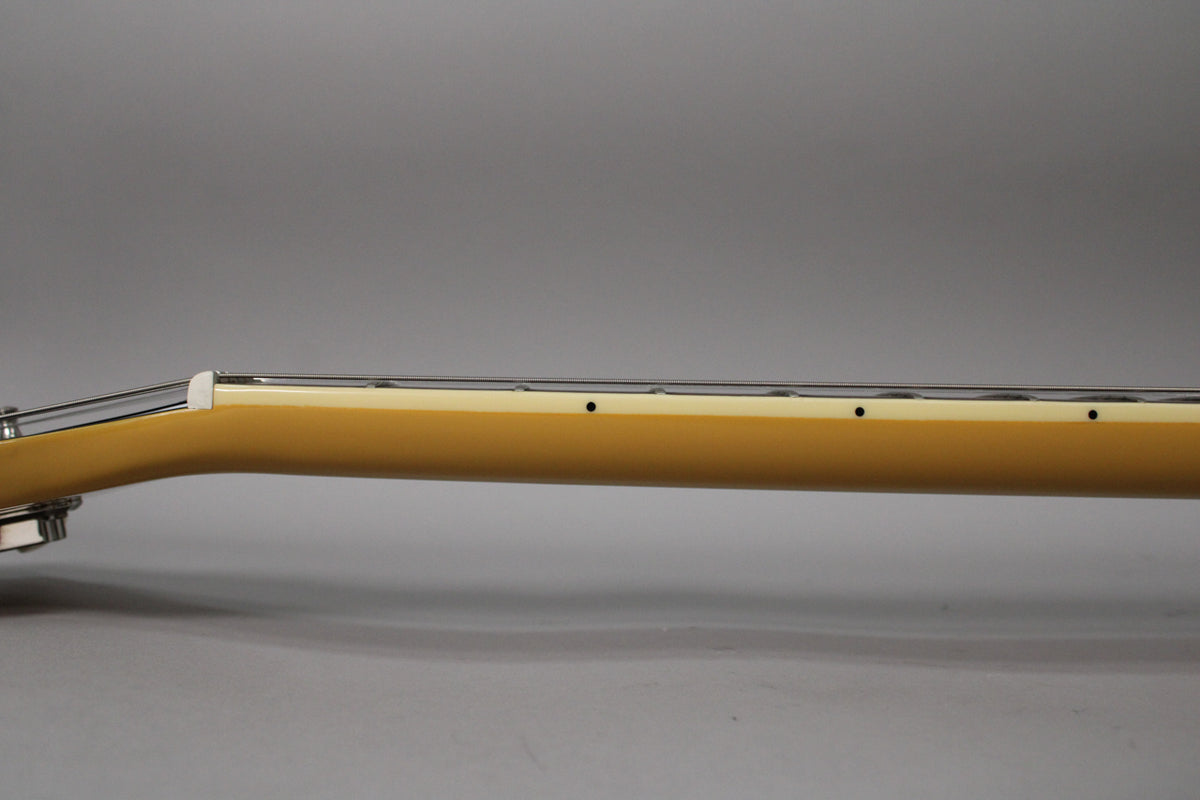 The guitar's TV Yellow neck and fretboard are shown from the side, with black dot inlays and a white nut.