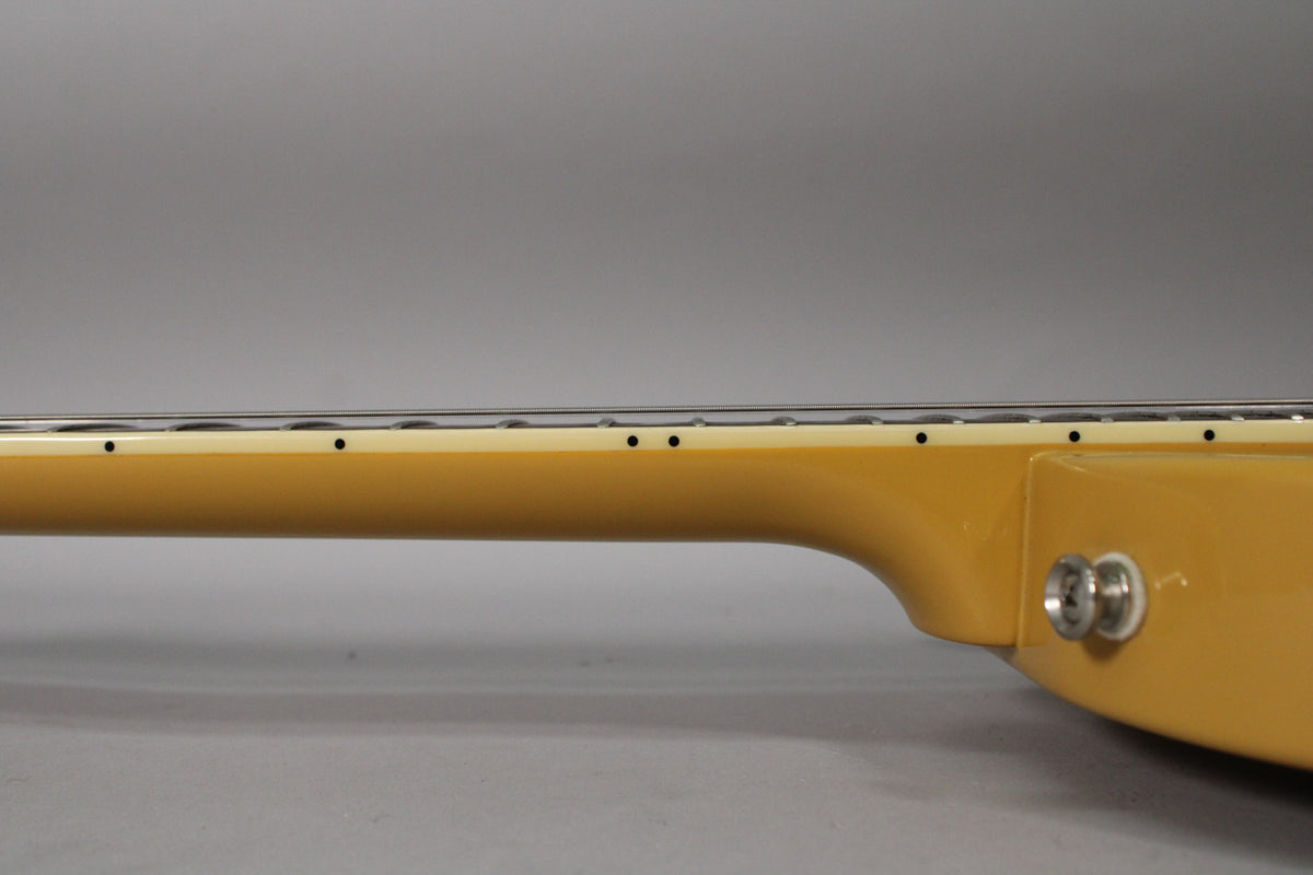 Side view of a TV yellow guitar neck and upper body, showing the fretboard, strings, and strap button.