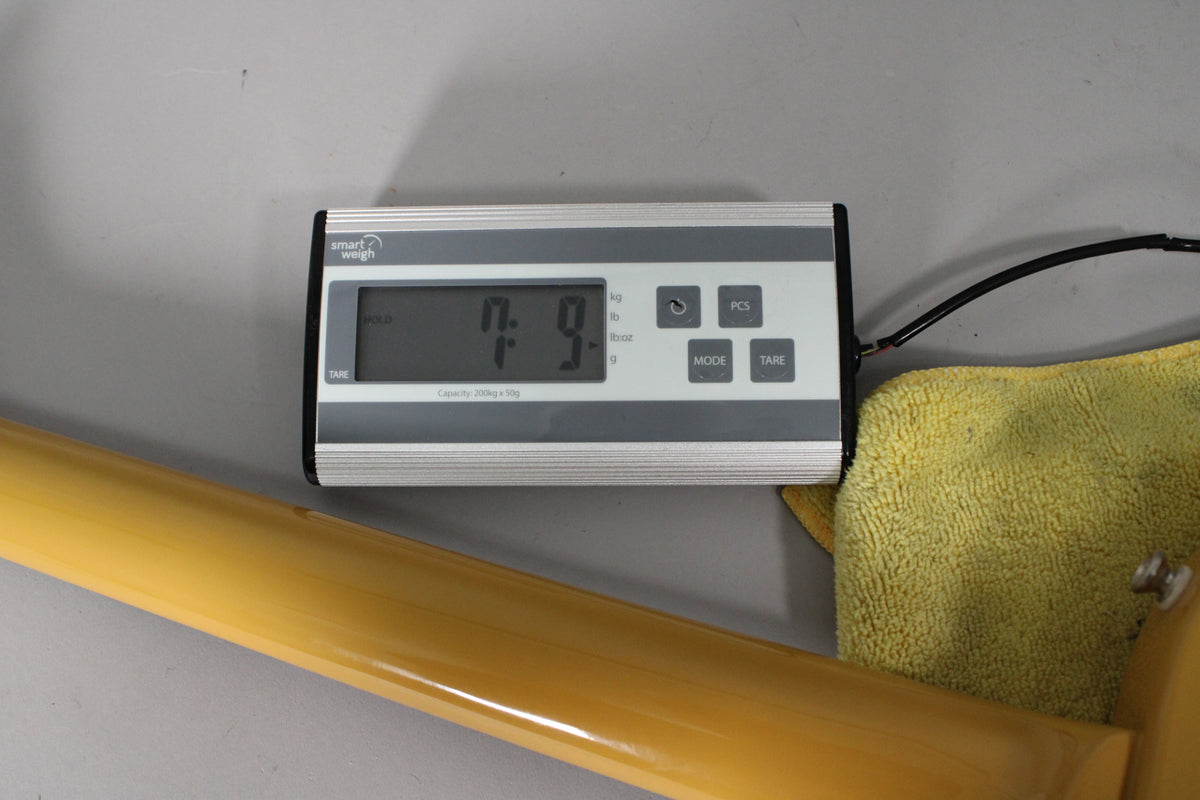 The guitar's TV Yellow body and neck are shown on a scale displaying "7.9" pounds, resting on a yellow towel.