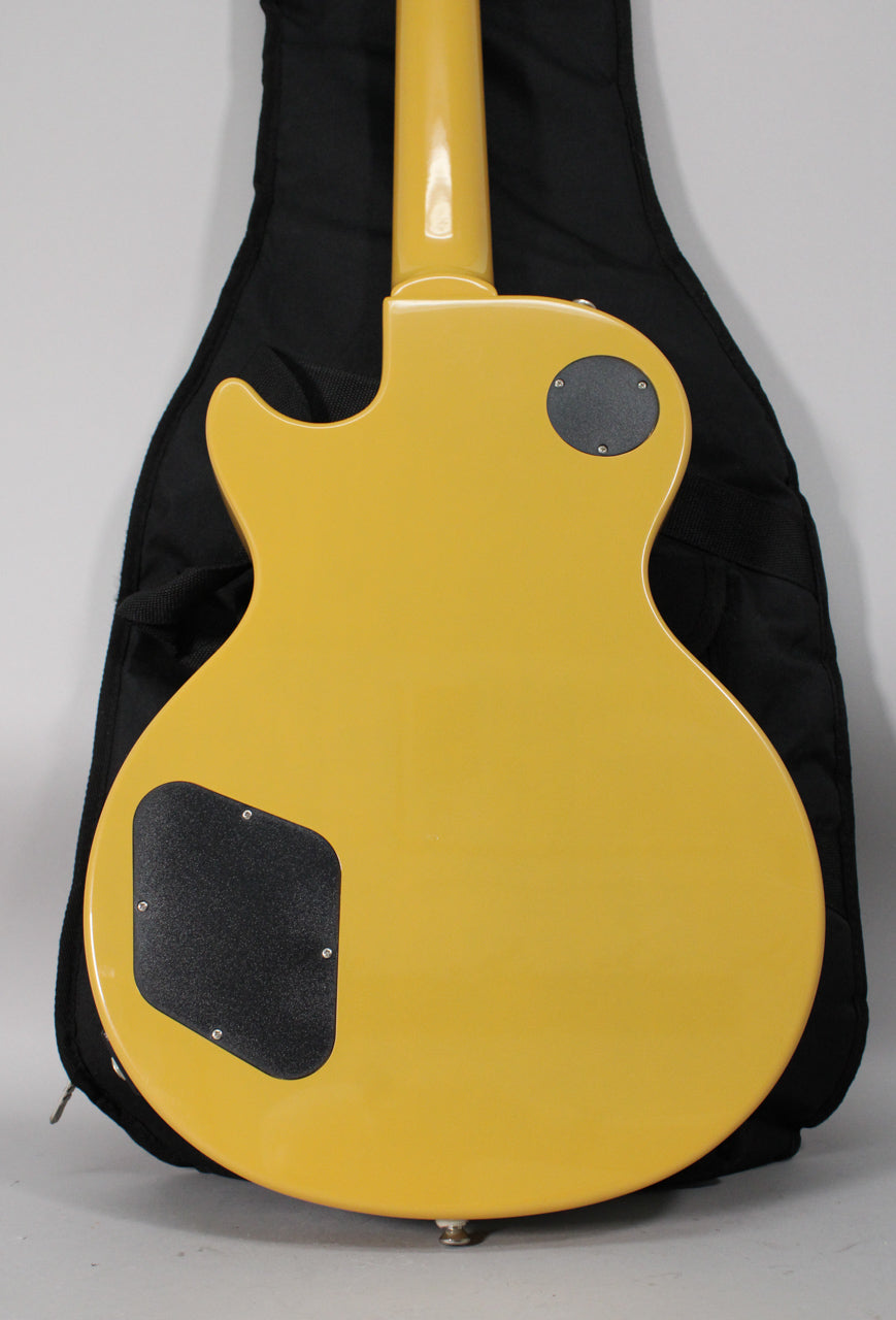 The back of a TV yellow guitar, showing the neck joint, two black control cavity covers, and a strap button.