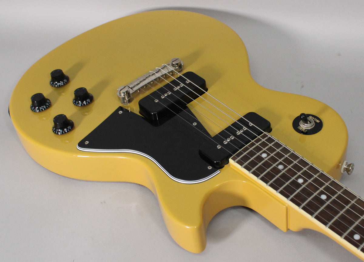 The TV Yellow guitar body is angled from the upper left, showing the black pickguard, two P90 pickups, and four black control knobs.