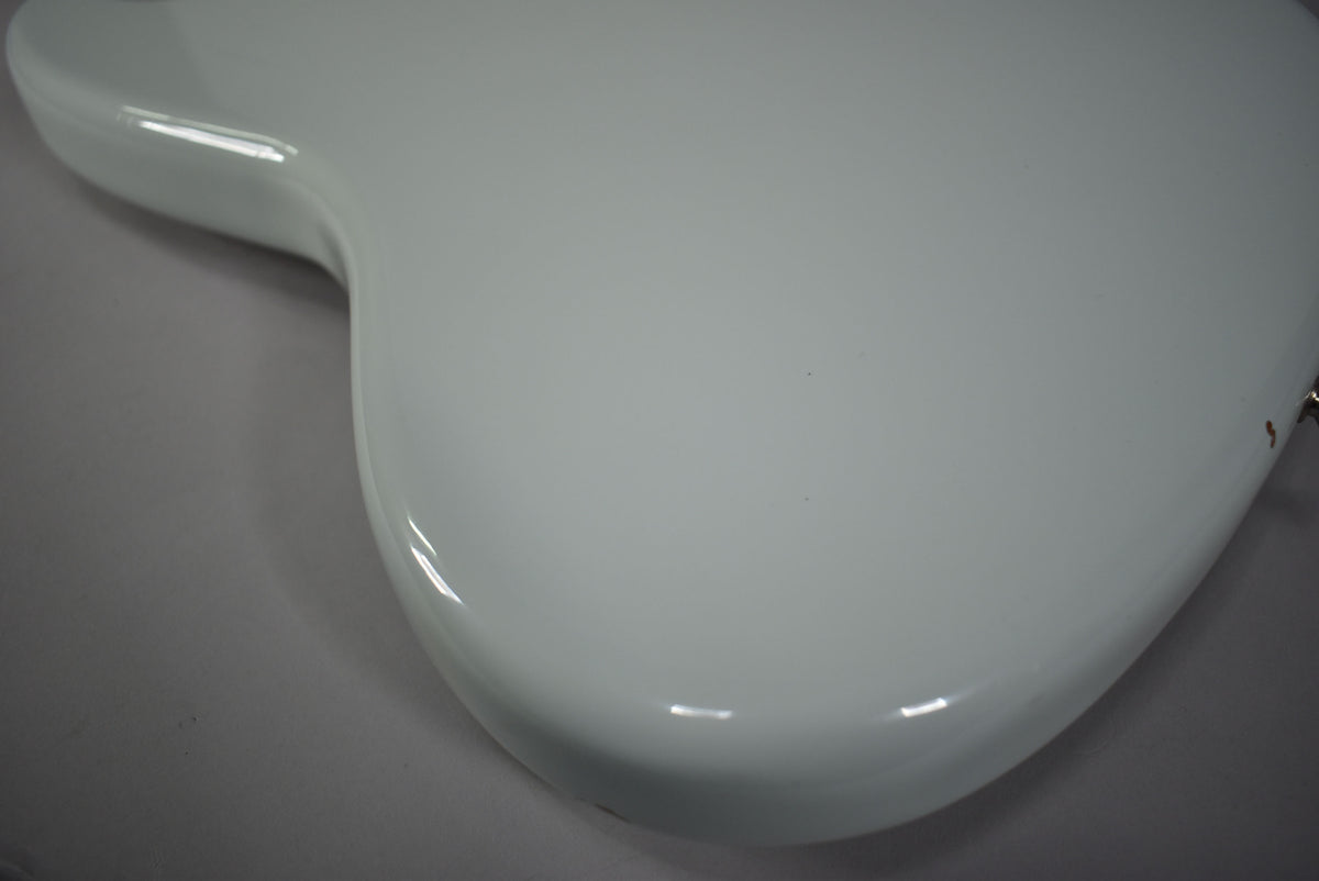 Close-up of the bass guitar's upper body, showing the smooth, glossy sonic blue finish with a few tiny dark specks.