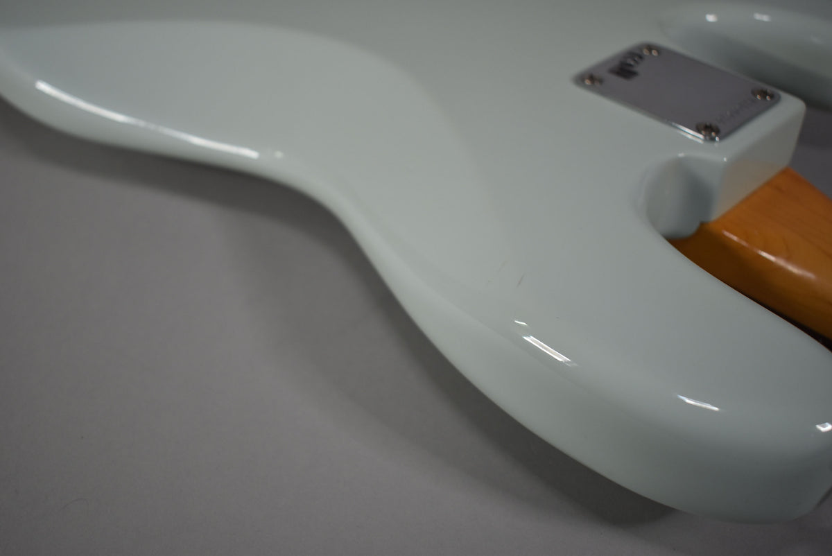 The bass's glossy sonic blue body curves from the lower horn to the neck plate, showing a few small scuffs.