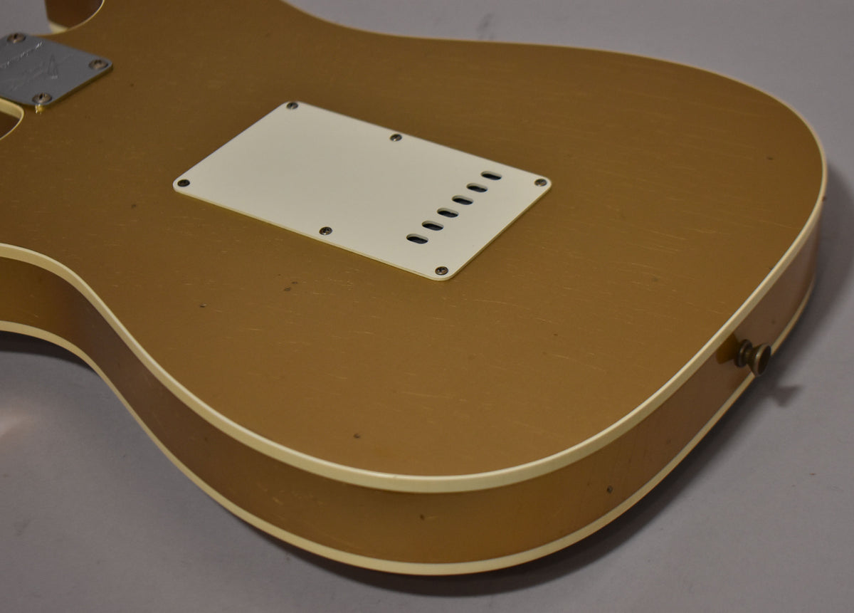The back of the Aztec gold guitar shows a white tremolo cover, output jack, and light relic wear with visible checking.