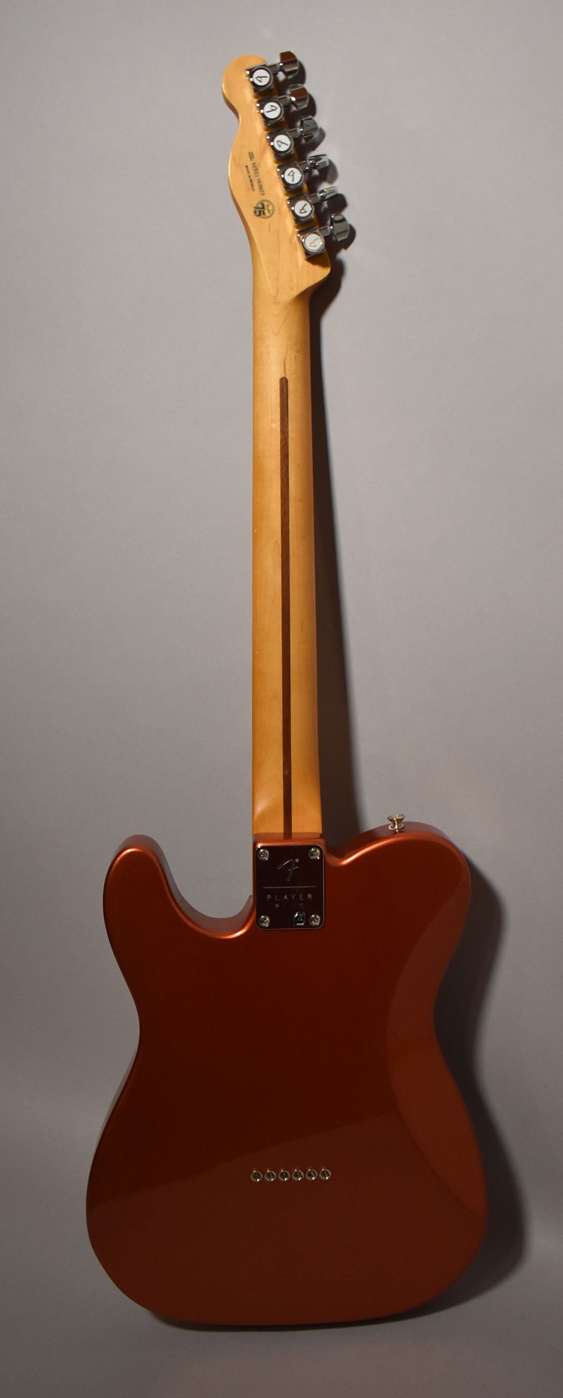 The back of a glossy candy apple red Telecaster, showing the maple neck, chrome tuners, and string-through-body ferrules.