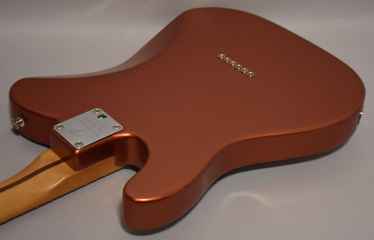 The guitar's metallic candy apple red back is angled, showing the neck plate, strap button, and six string-through-body ferrules.