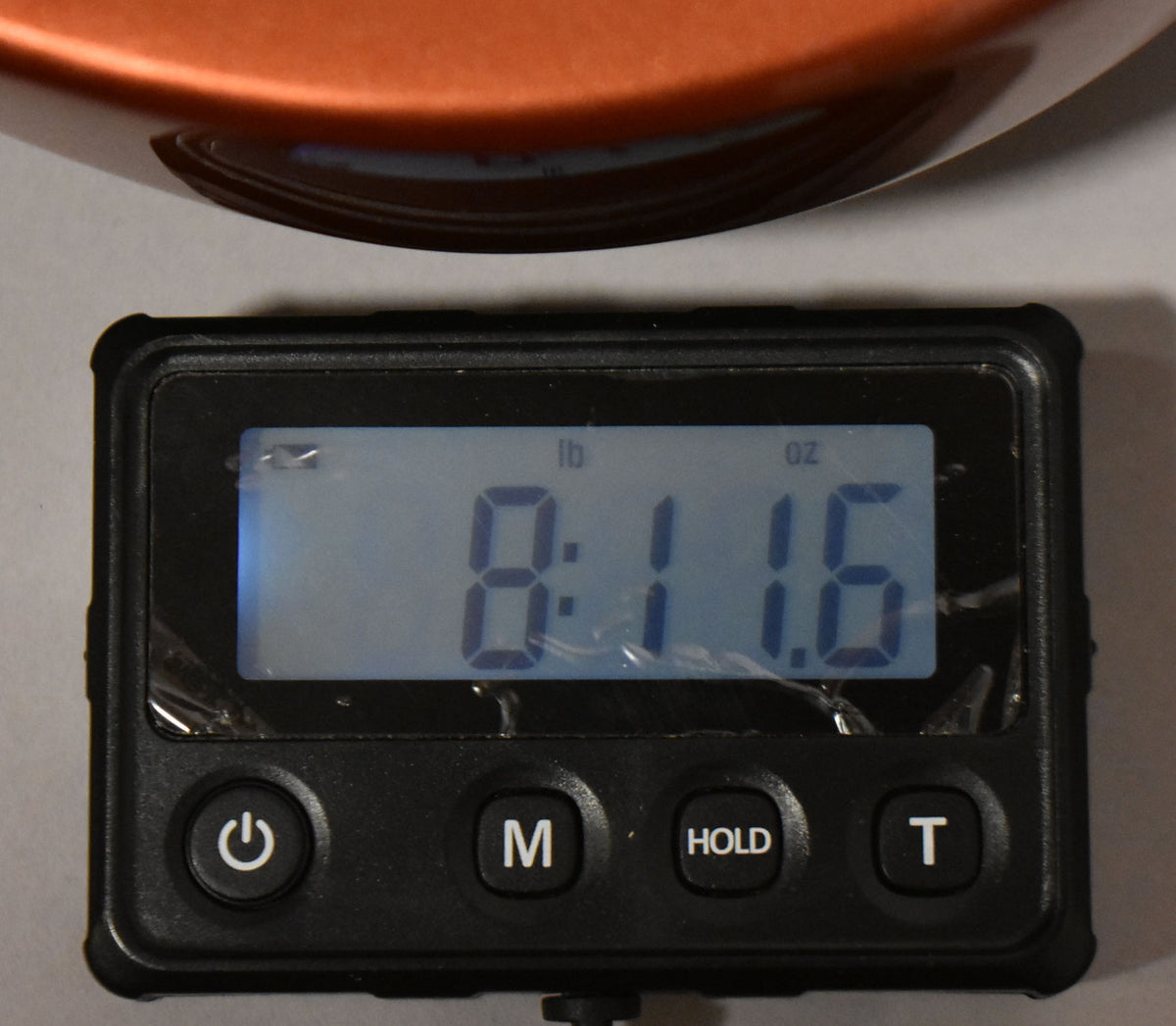 A digital scale displays "8:11.6" lbs, with a small portion of the guitar's candy apple red body visible at the top.
