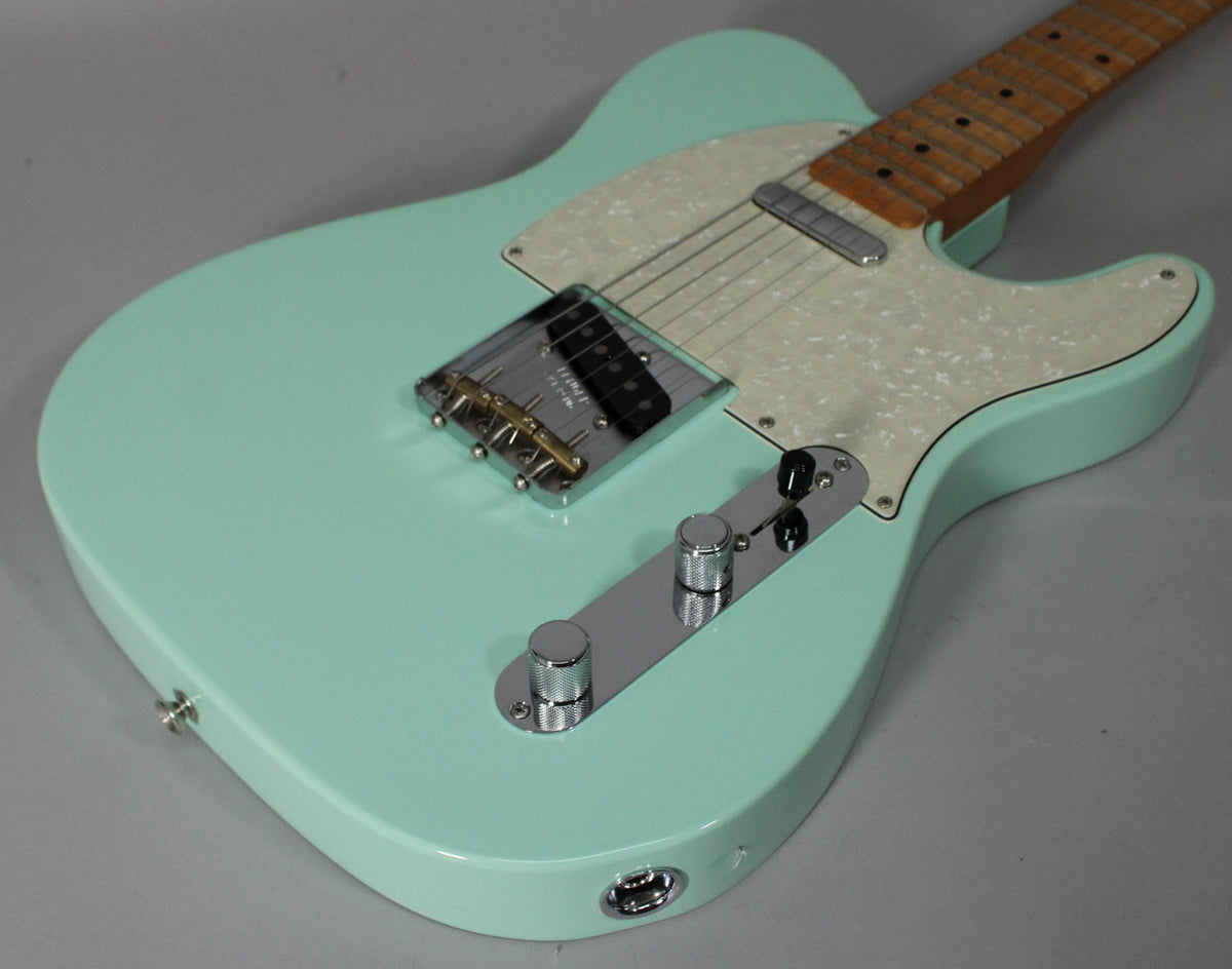 Surf green Telecaster body, angled from above, showing a pearloid pickguard, chrome bridge, control plate, and two knobs.