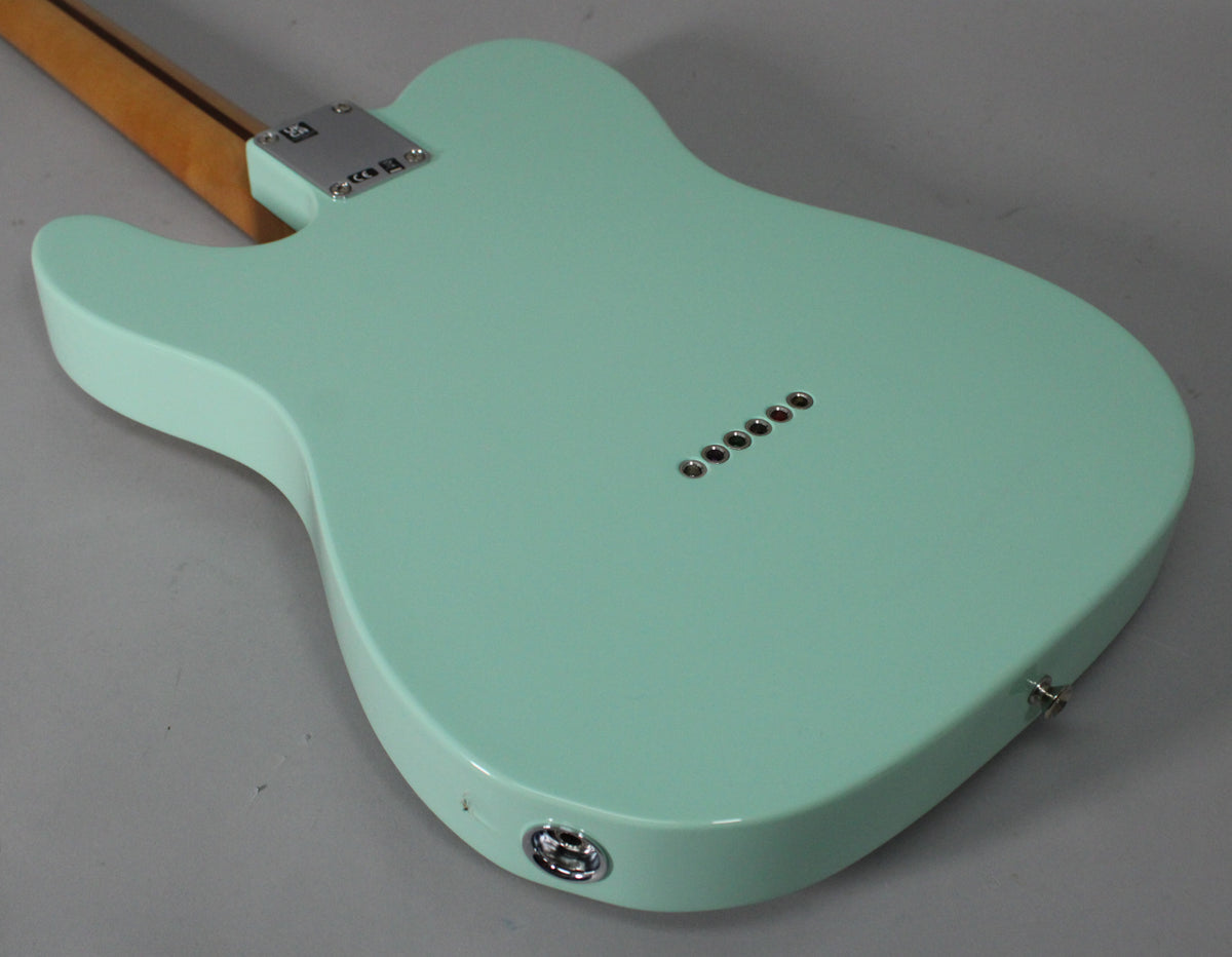 The back of a surf green Telecaster, angled to show the neck plate, six string-through-body ferrules, and output jack.