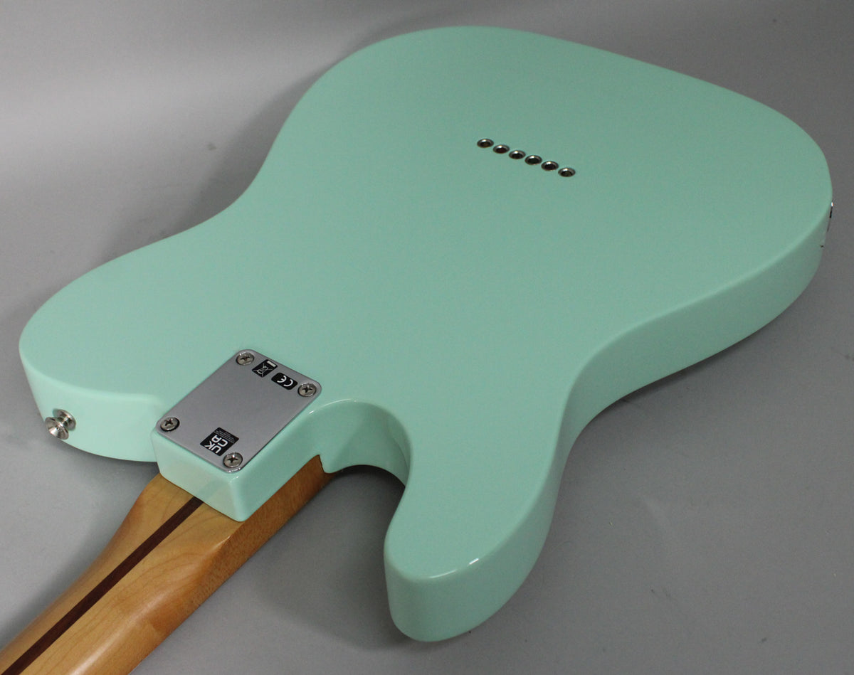 The back of a Surf Green Telecaster, showing the neck plate, string-through-body ferrules, and a light maple neck.