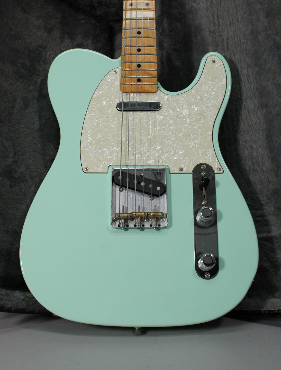 Full body shot of a surf green Telecaster with a pearloid pickguard, maple neck, and chrome hardware.