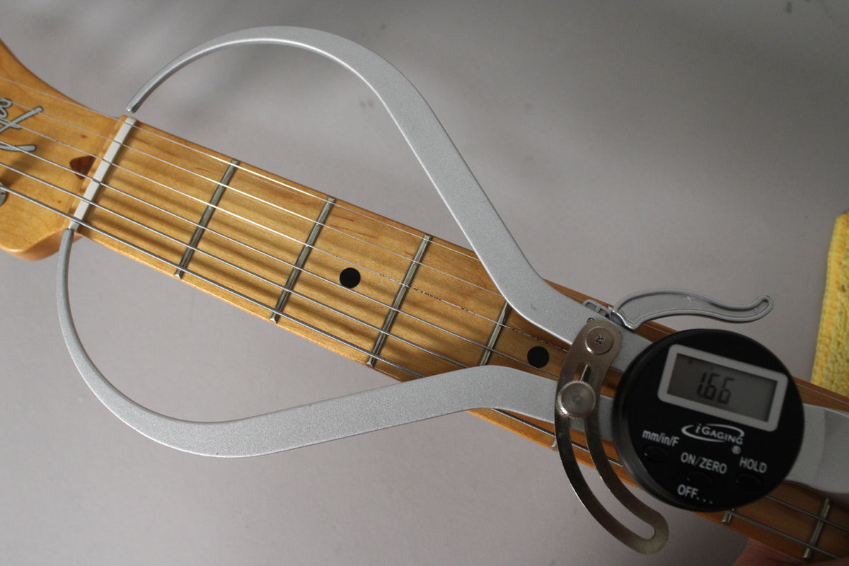 Close-up of the maple fretboard with a digital fret rocker showing a 1.66mm reading, indicating fret height.