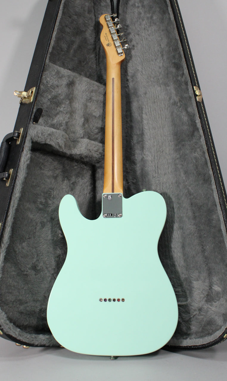 The Surf Green Telecaster is seen from the back, showing its light wood neck, chrome tuners, and six string-through-body ferrules.