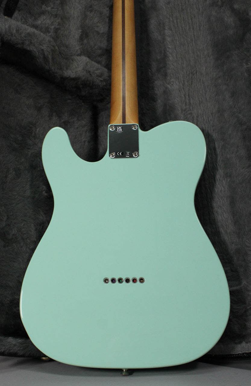 The back of a Surf Green Telecaster, showing the neck plate, string-through-body ferrules, and a light-colored wooden neck.