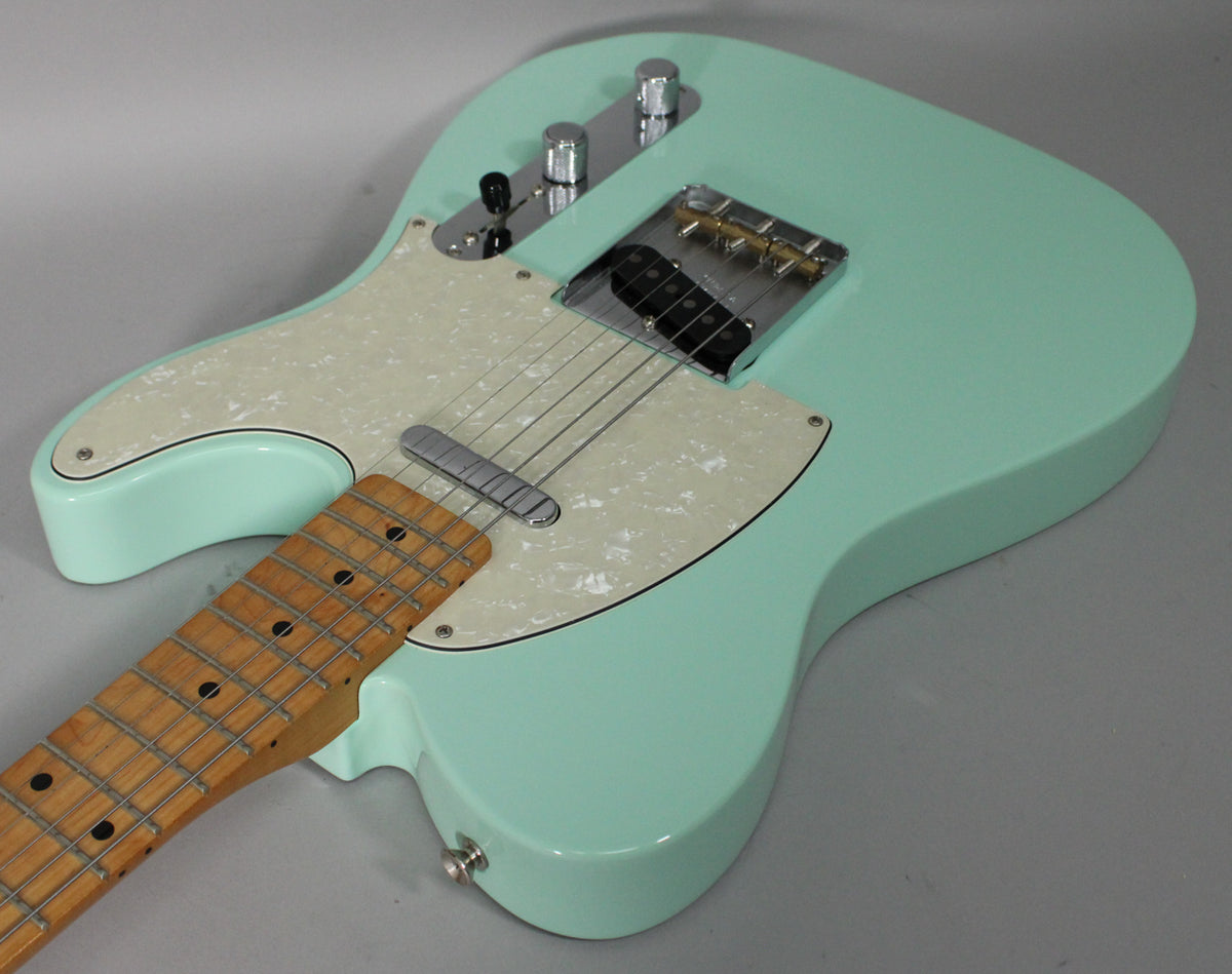Surf green Telecaster body with a pearloid pickguard, chrome hardware, and a maple fretboard, viewed from above.