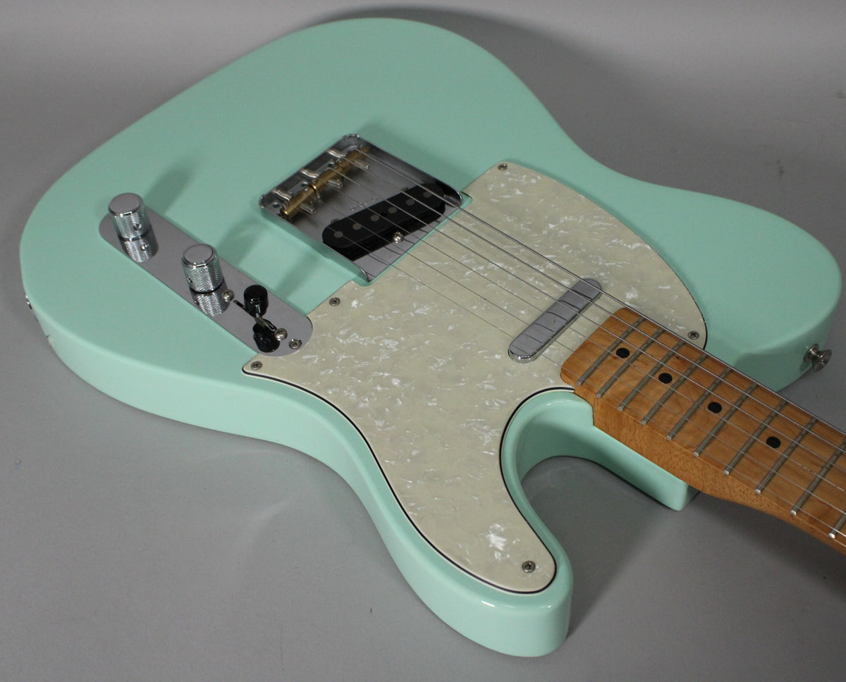 Surf green Telecaster body with a pearloid pickguard, chrome control plate, and a light maple neck, viewed from above.