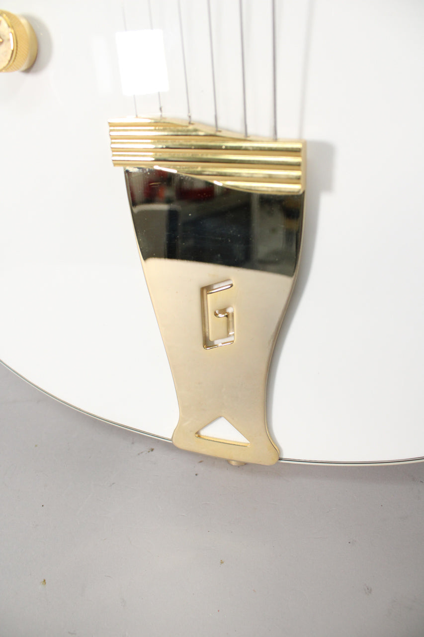 Close-up of the guitar's lower bout, showing the gold G-cutout tailpiece and strings against the white body.